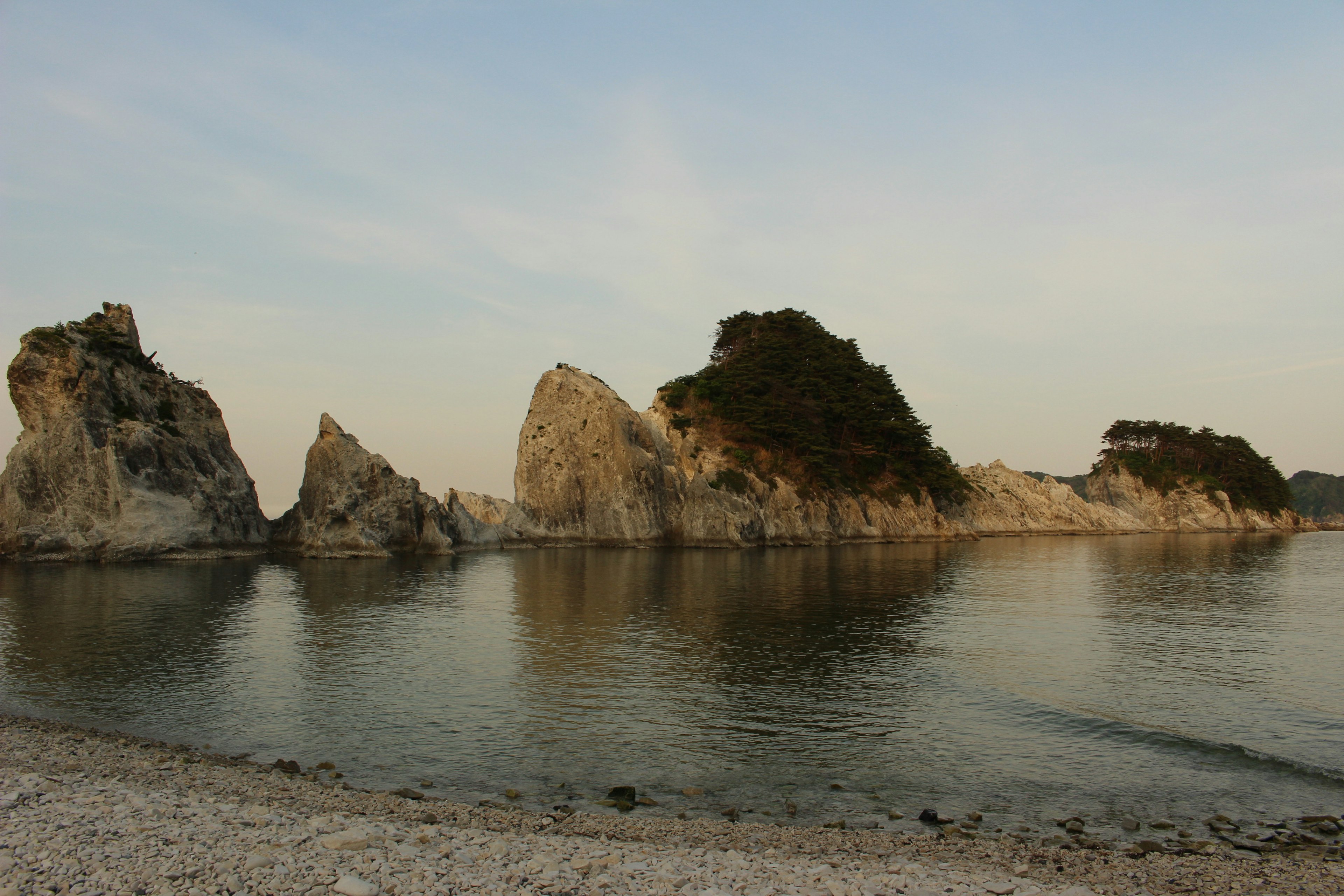 静かな海に浮かぶ岩の群れと穏やかな空の風景