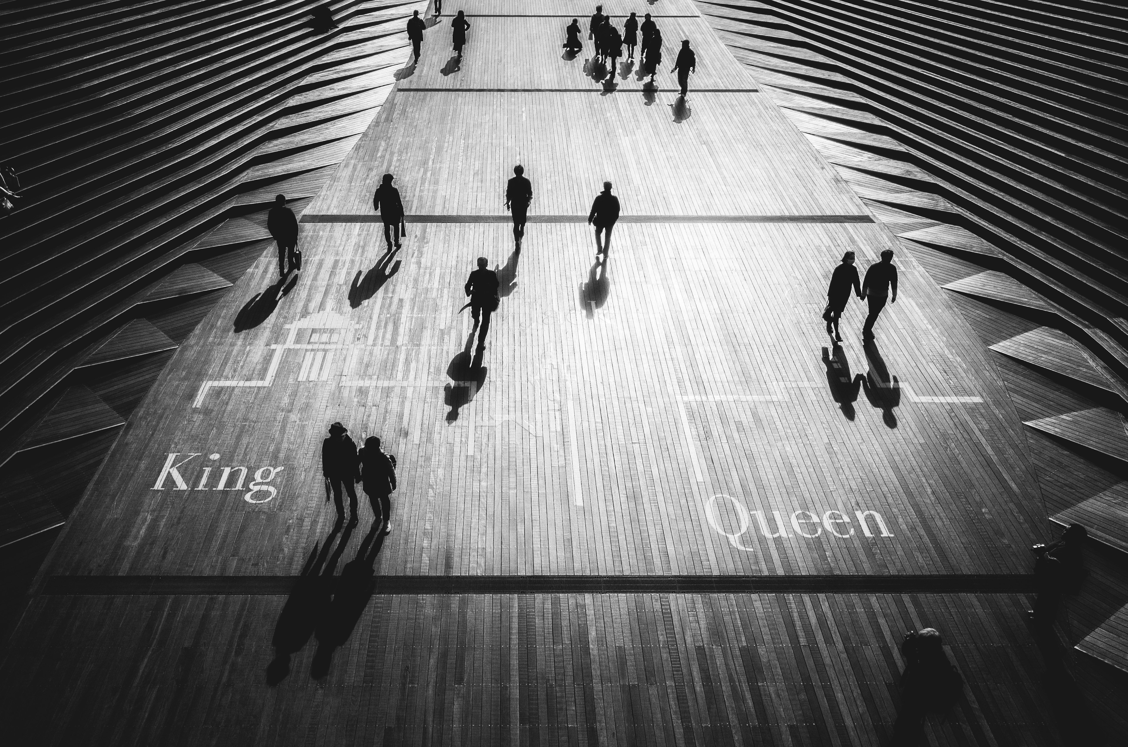 People walking on a wooden floor featuring the words King and Queen in black and white