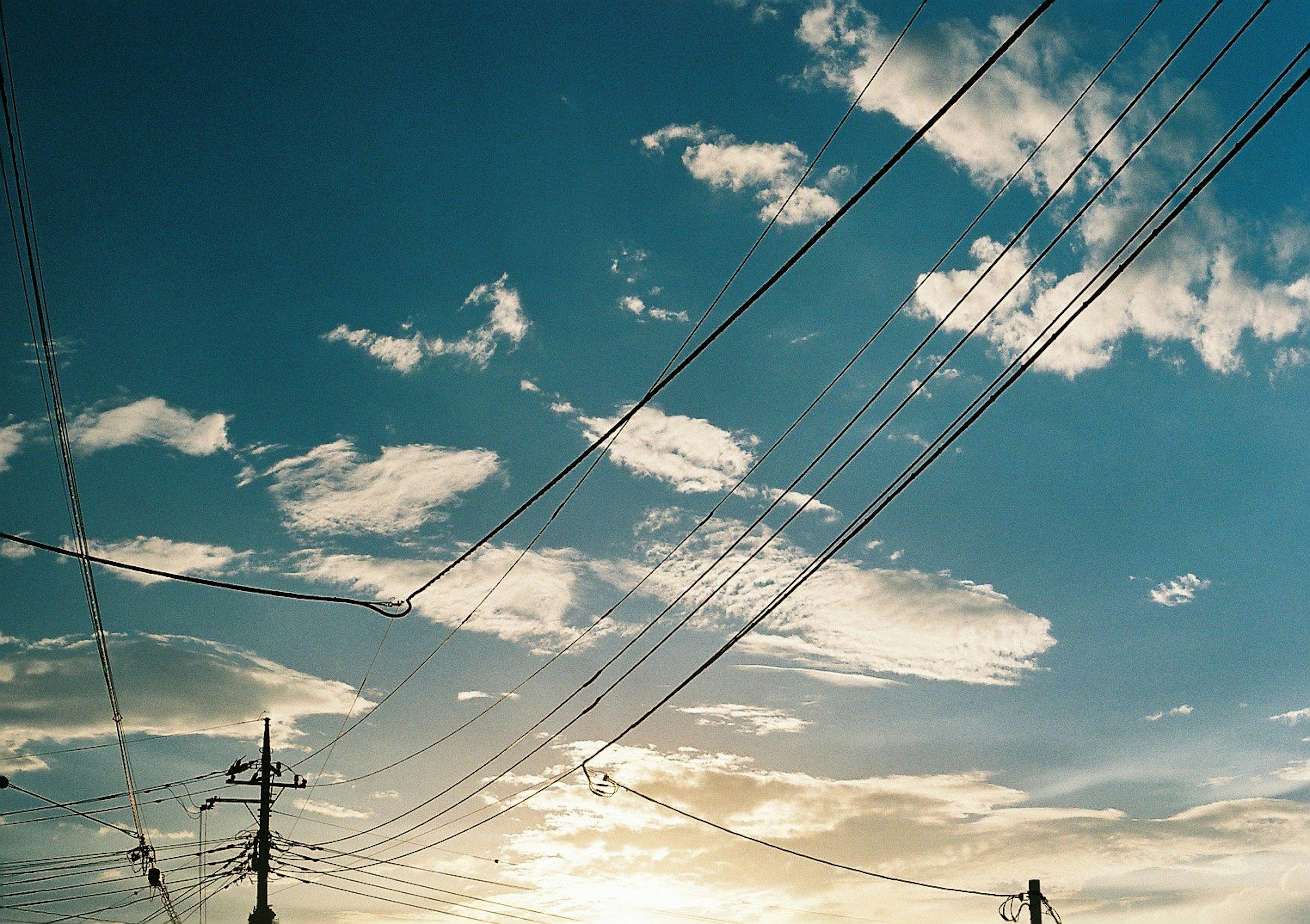 Silhouette de lignes électriques contre un ciel bleu avec des nuages