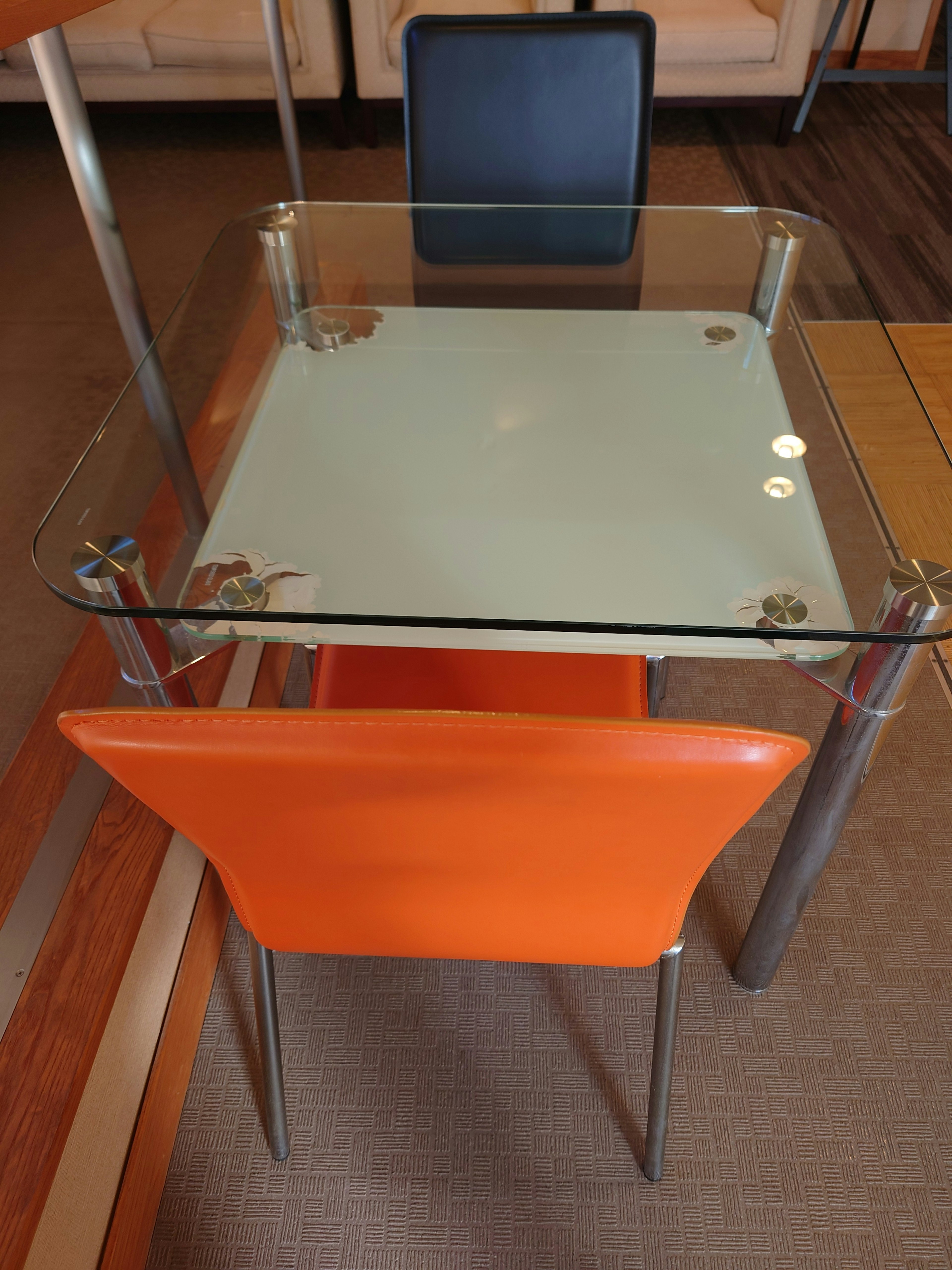 Table en verre avec une chaise orange et une chaise noire