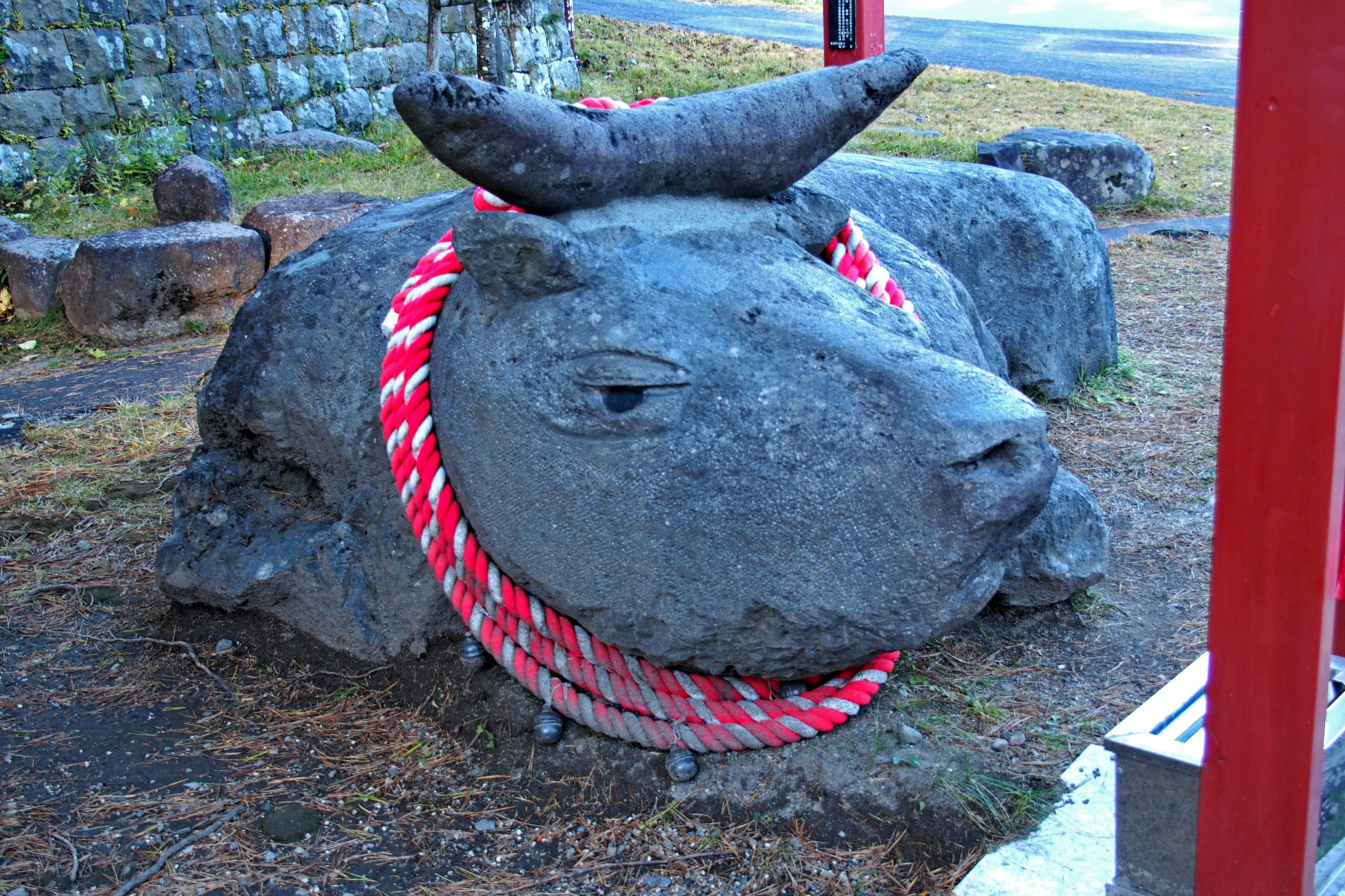 Escultura de piedra de una vaca adornada con una cuerda roja y blanca