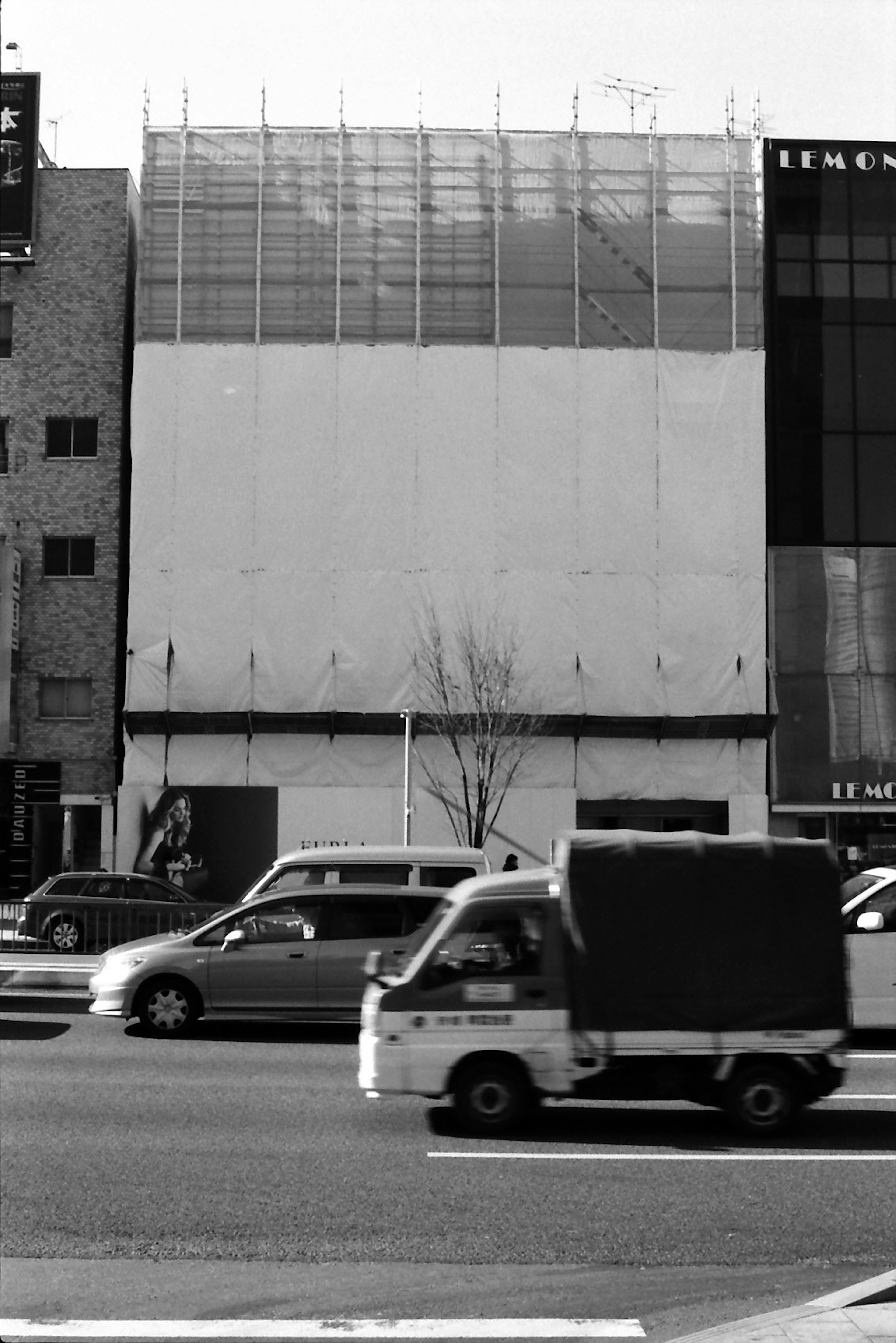 Paysage urbain en noir et blanc avec une façade de bâtiment et des véhicules en circulation