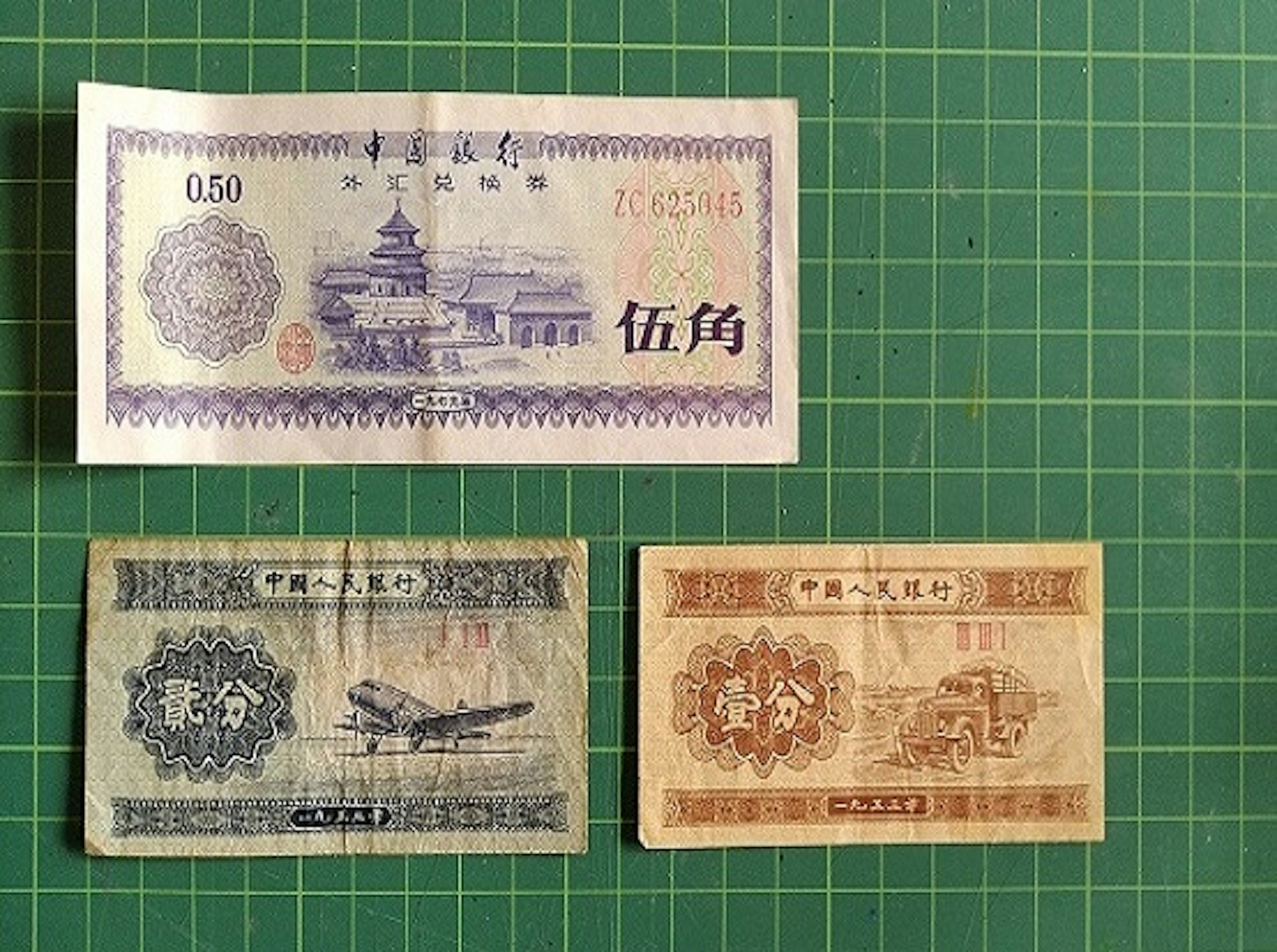 Tiga uang kertas China vintage dipajang di atas alas hijau