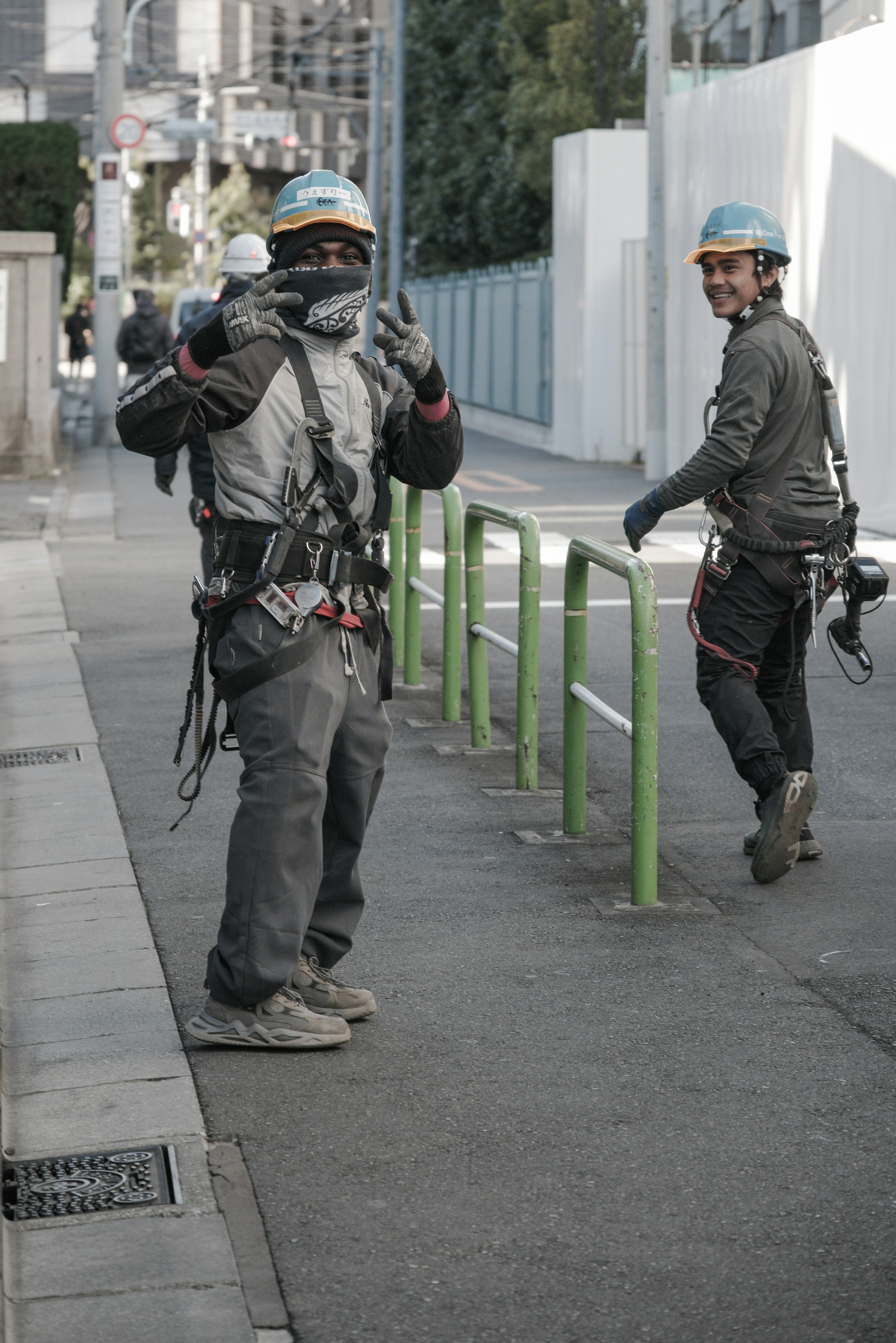 Two workers in safety gear smiling on a street One is giving a thumbs up