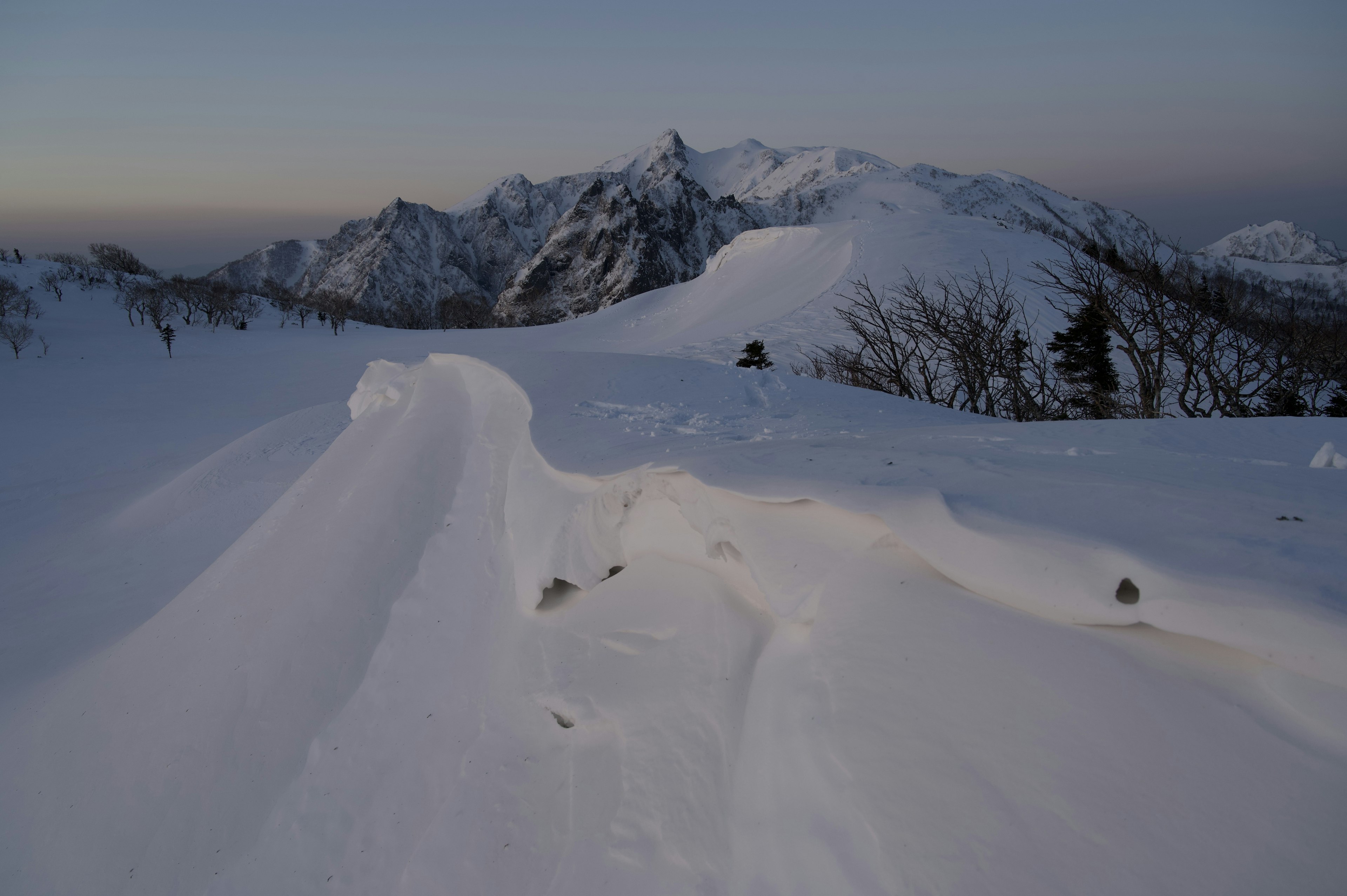 Paisaje montañoso cubierto de nieve con suaves ondulaciones de nieve