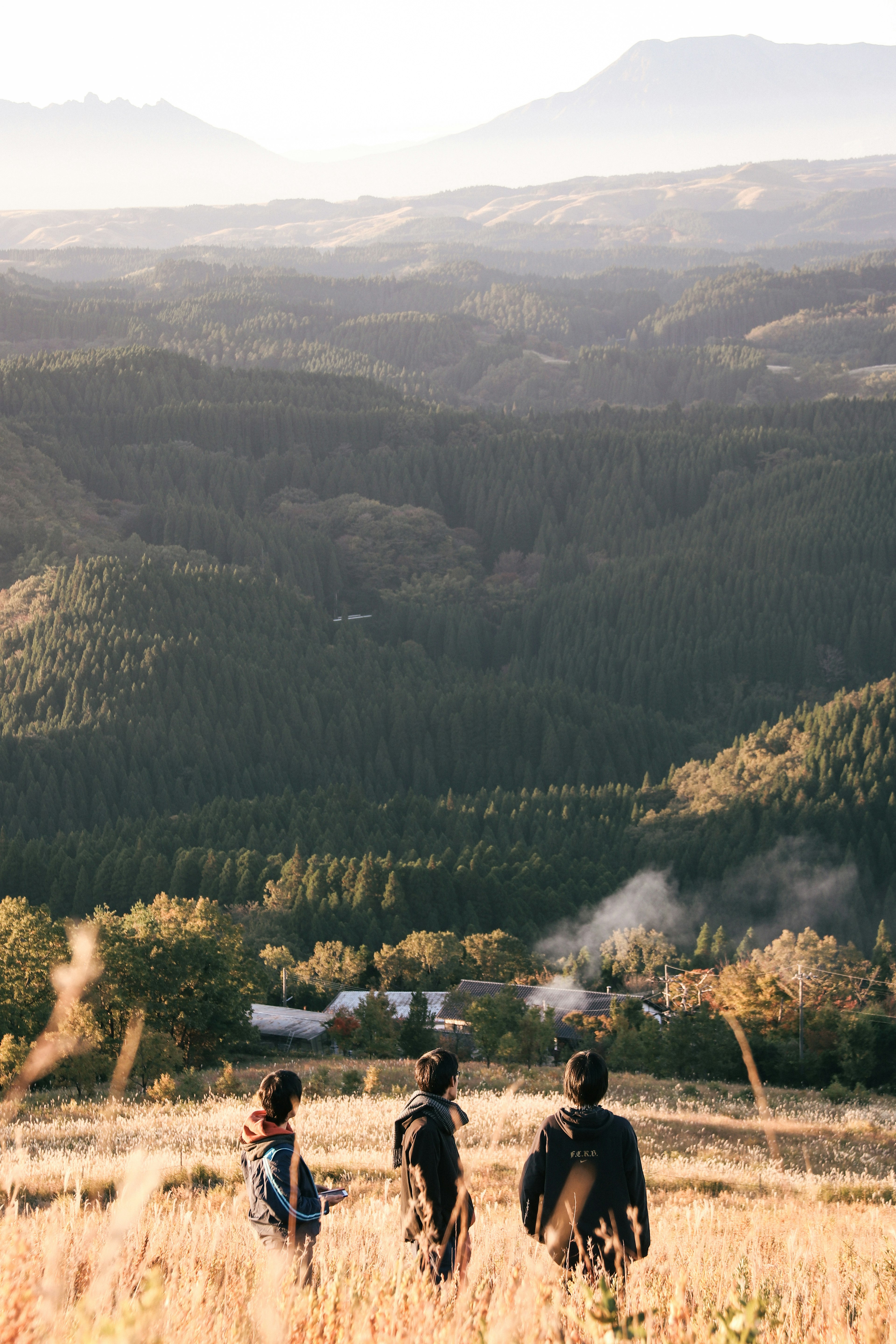 Drei Personen stehen auf einem Hügel und blicken auf eine weite Berglandschaft