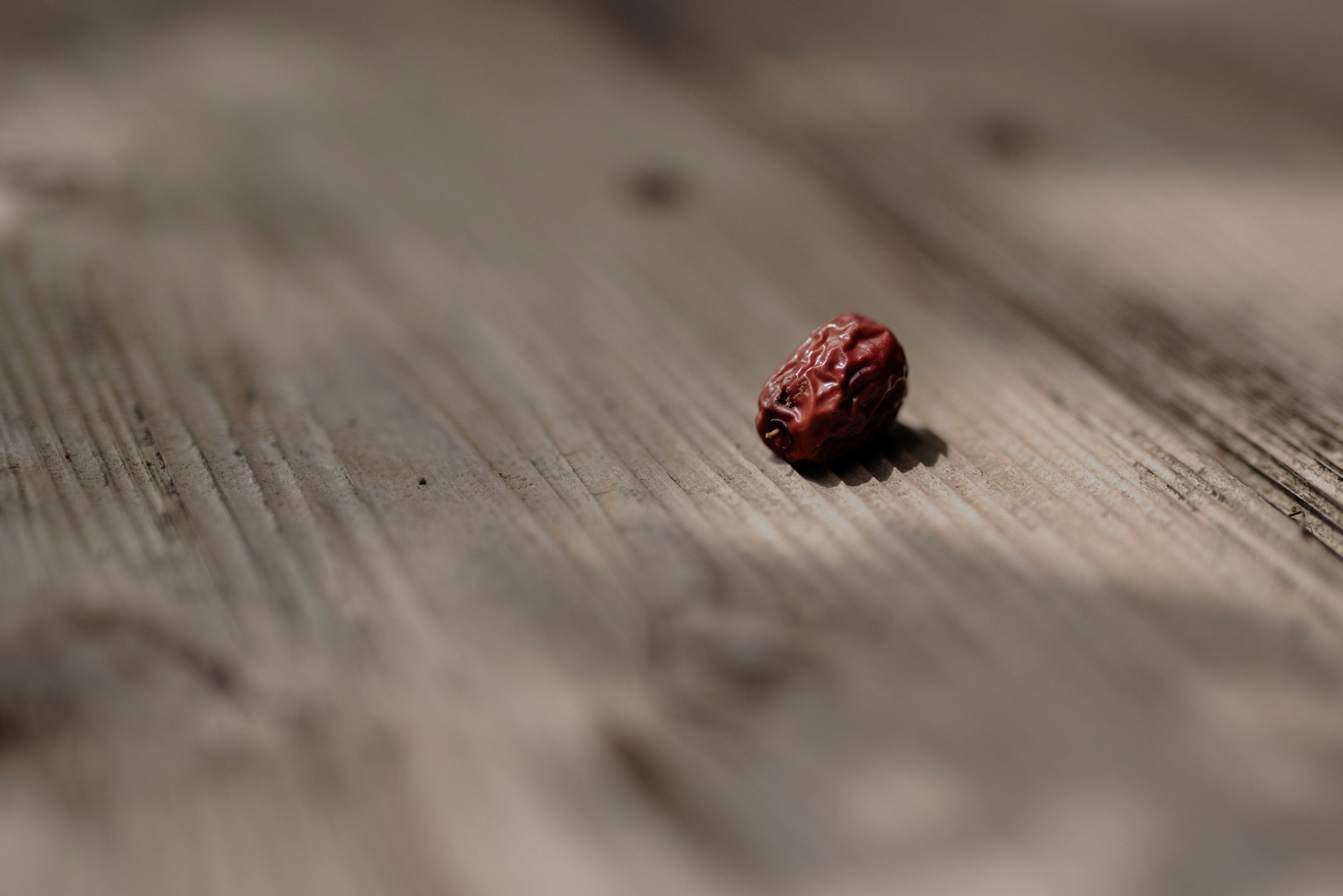 Una pequeña semilla roja colocada sobre una mesa de madera