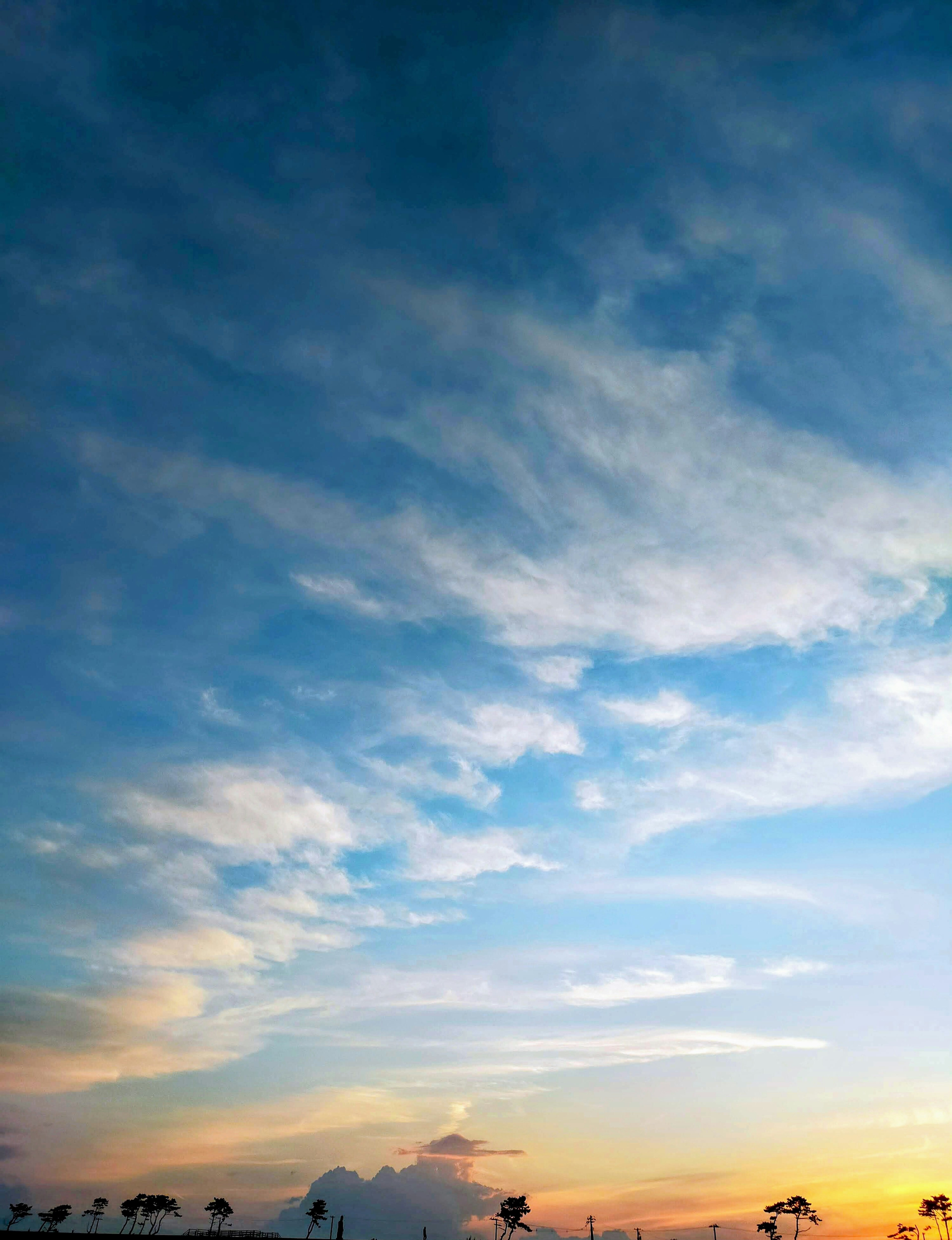 Langit biru dengan awan putih dan matahari terbenam oranye