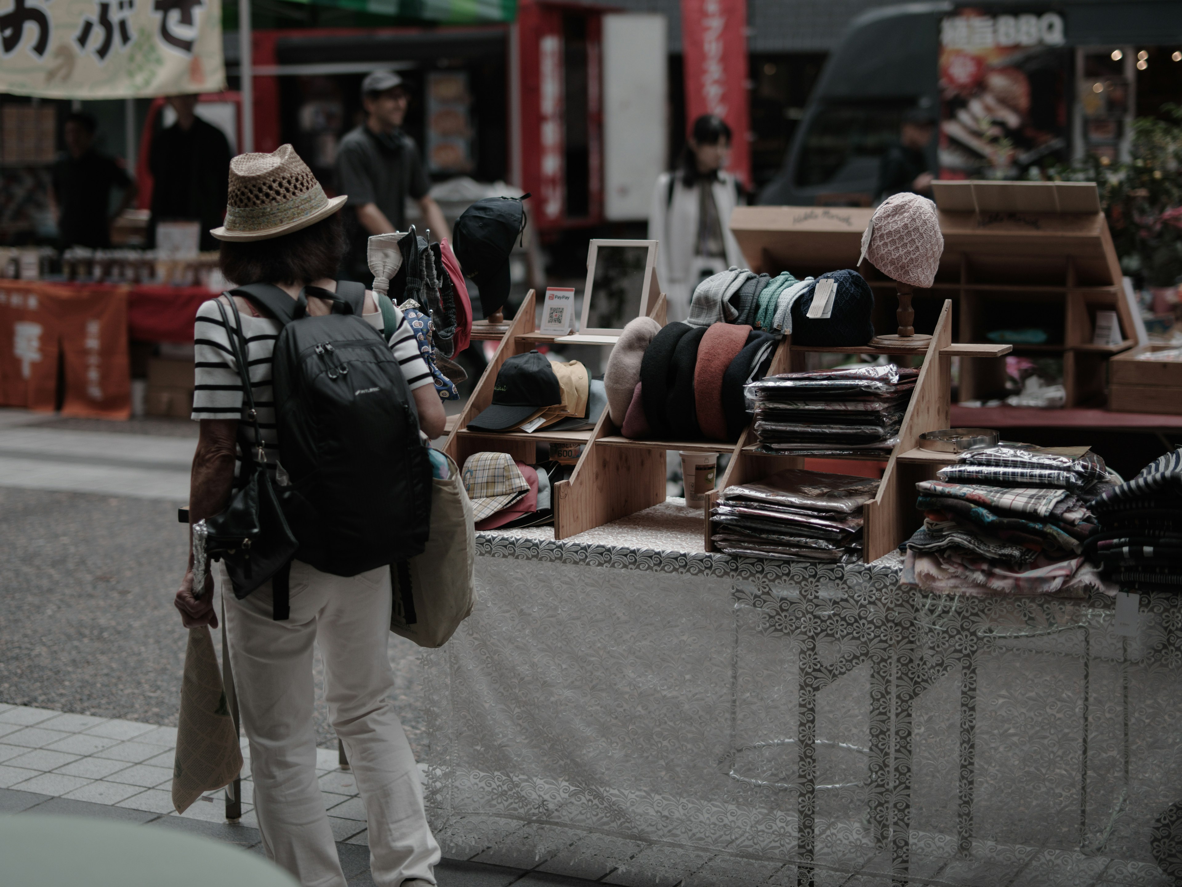 Una donna con un cappello che sfoglia articoli in un mercato di strada