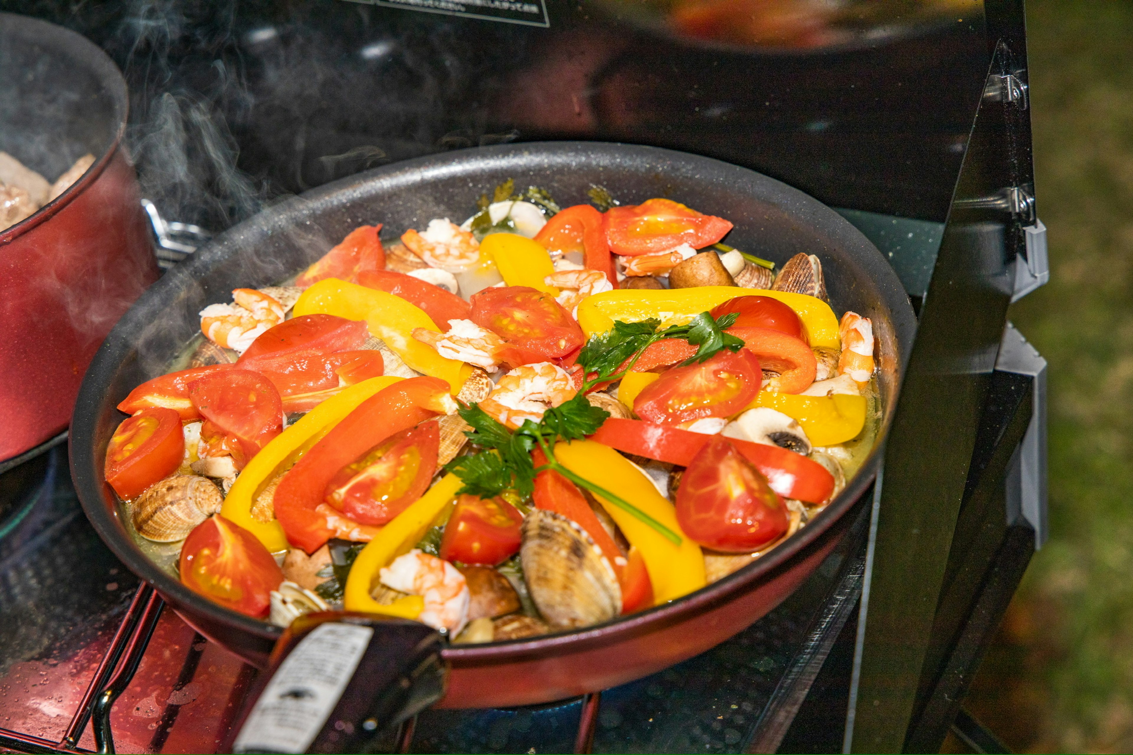 Sartén llena de verduras coloridas y mariscos cocinando en una estufa