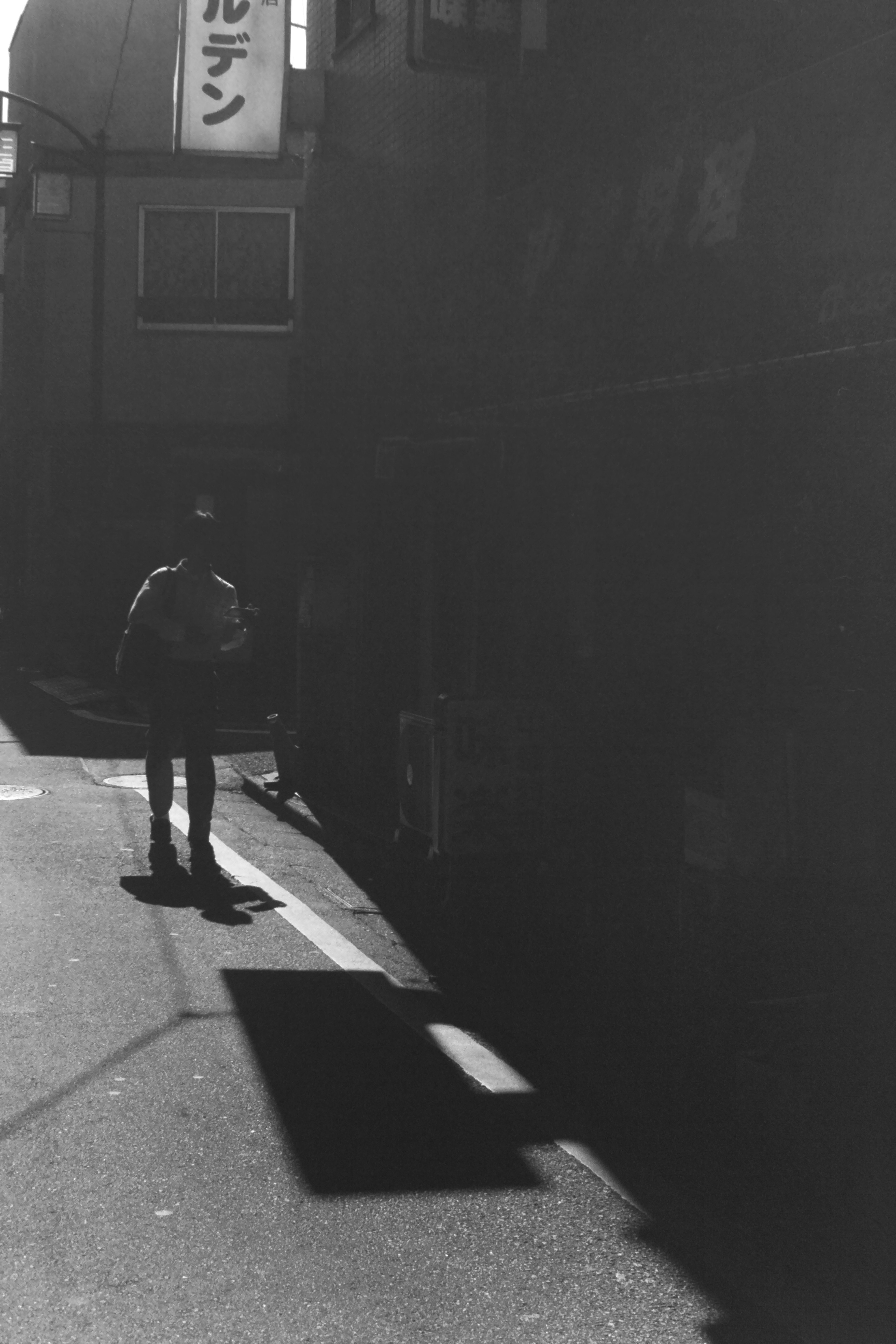 Contraste d'une personne debout dans une ruelle sombre avec des ombres