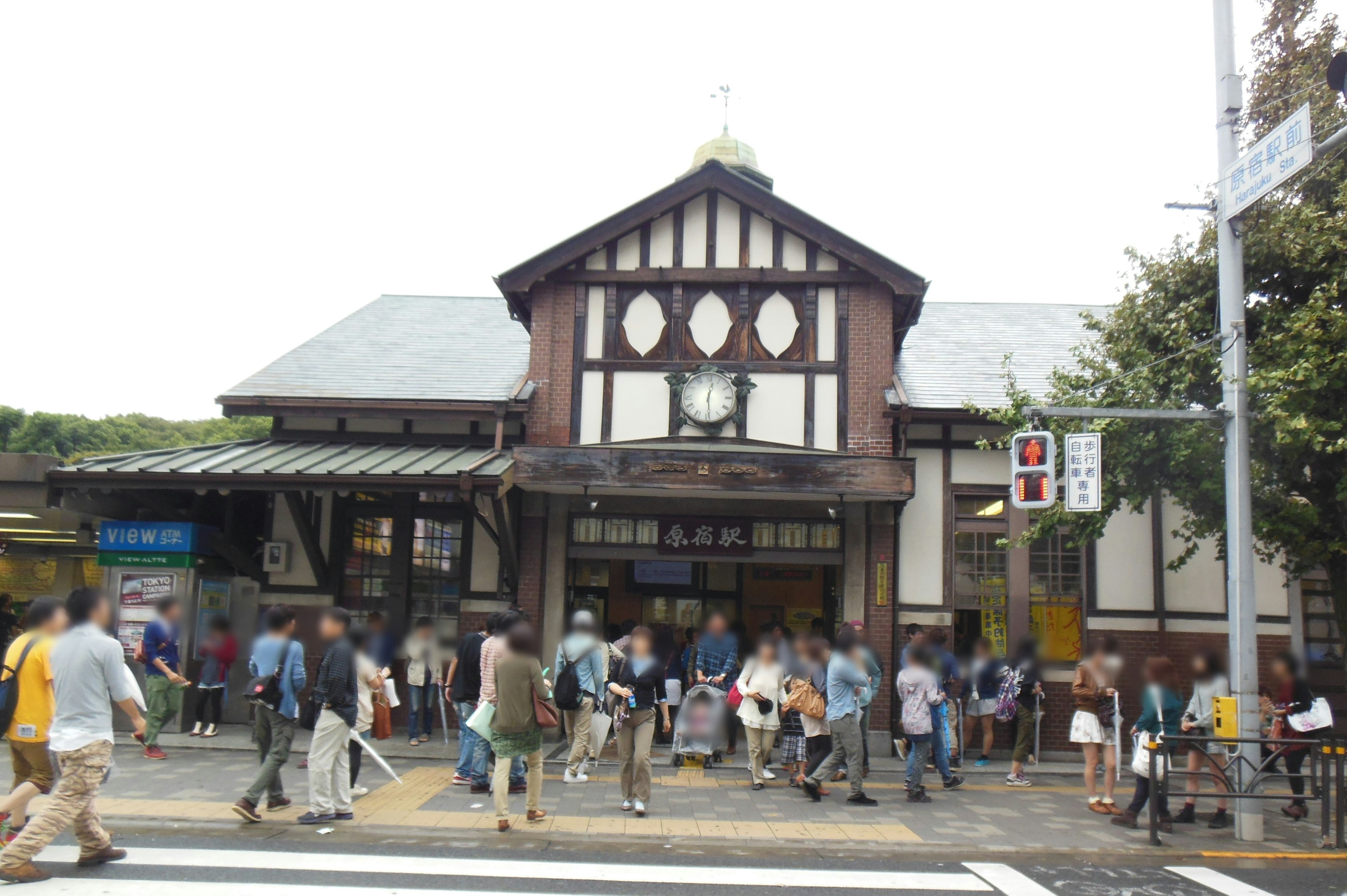 Exterior of a busy train station with traditional architectural style and many pedestrians