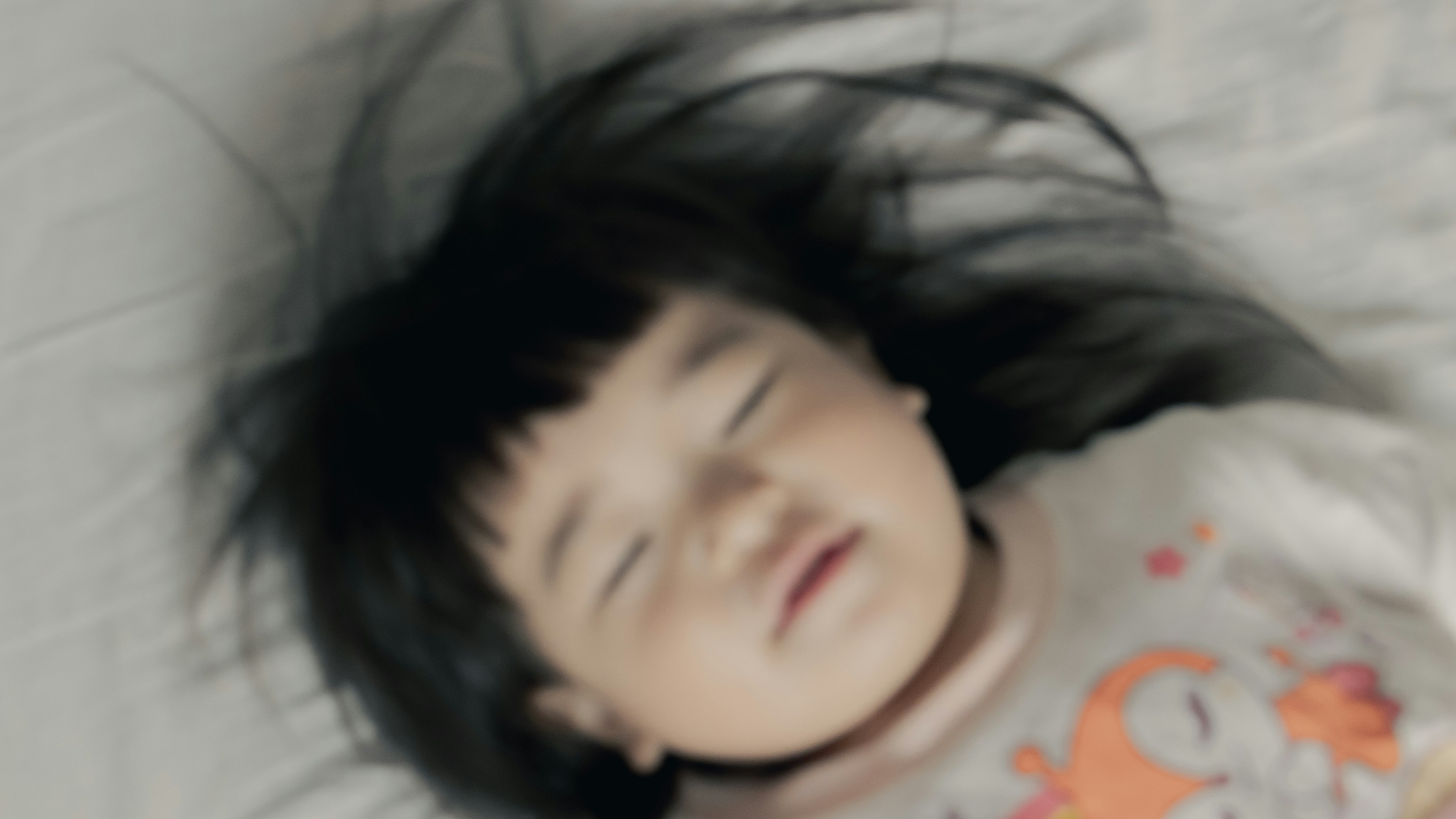 眠っている子供の顔　黒い髪が広がっている　かわいいパジャマを着ている