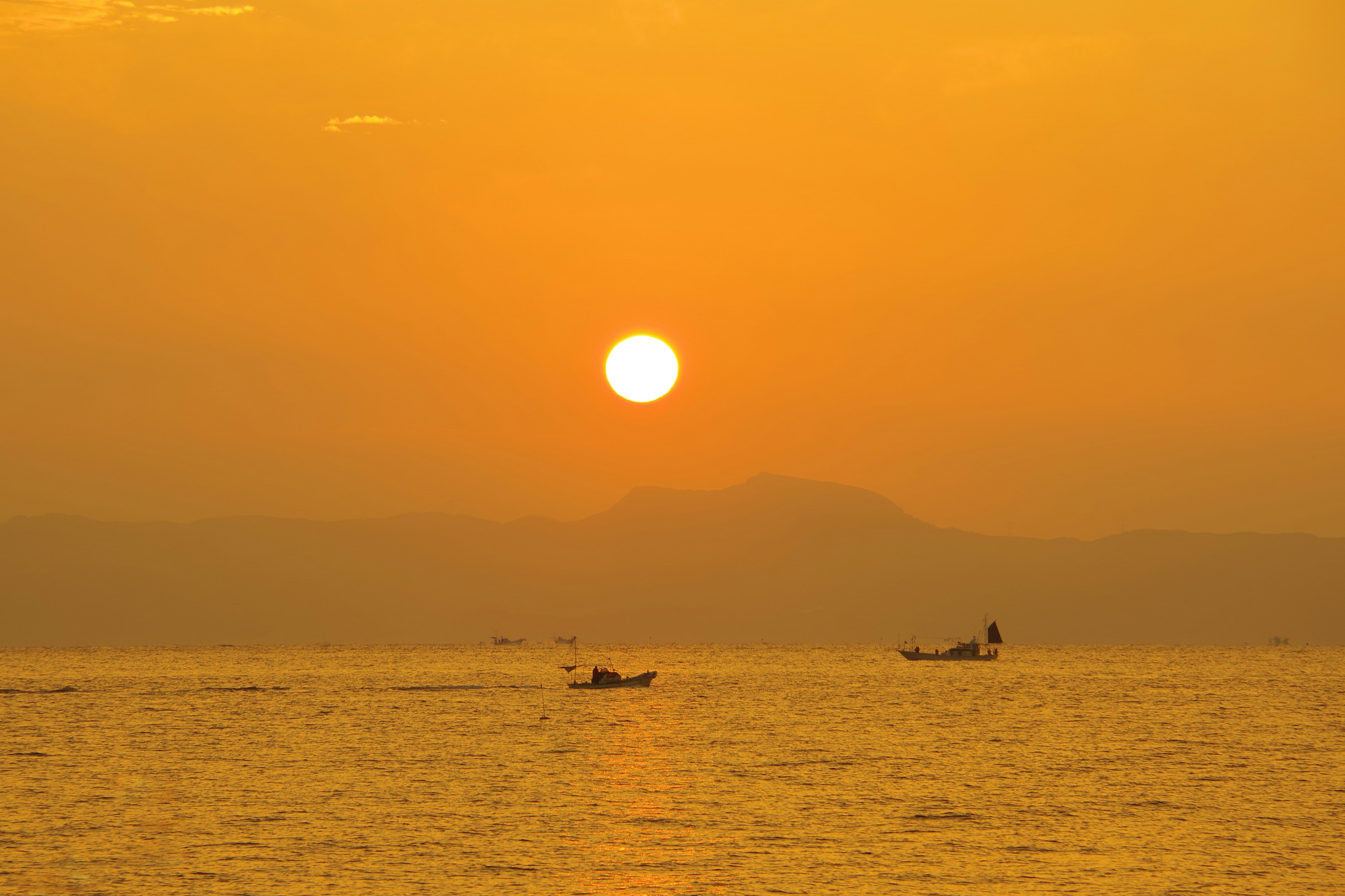 Paisaje marino al atardecer con pequeñas embarcaciones en el agua