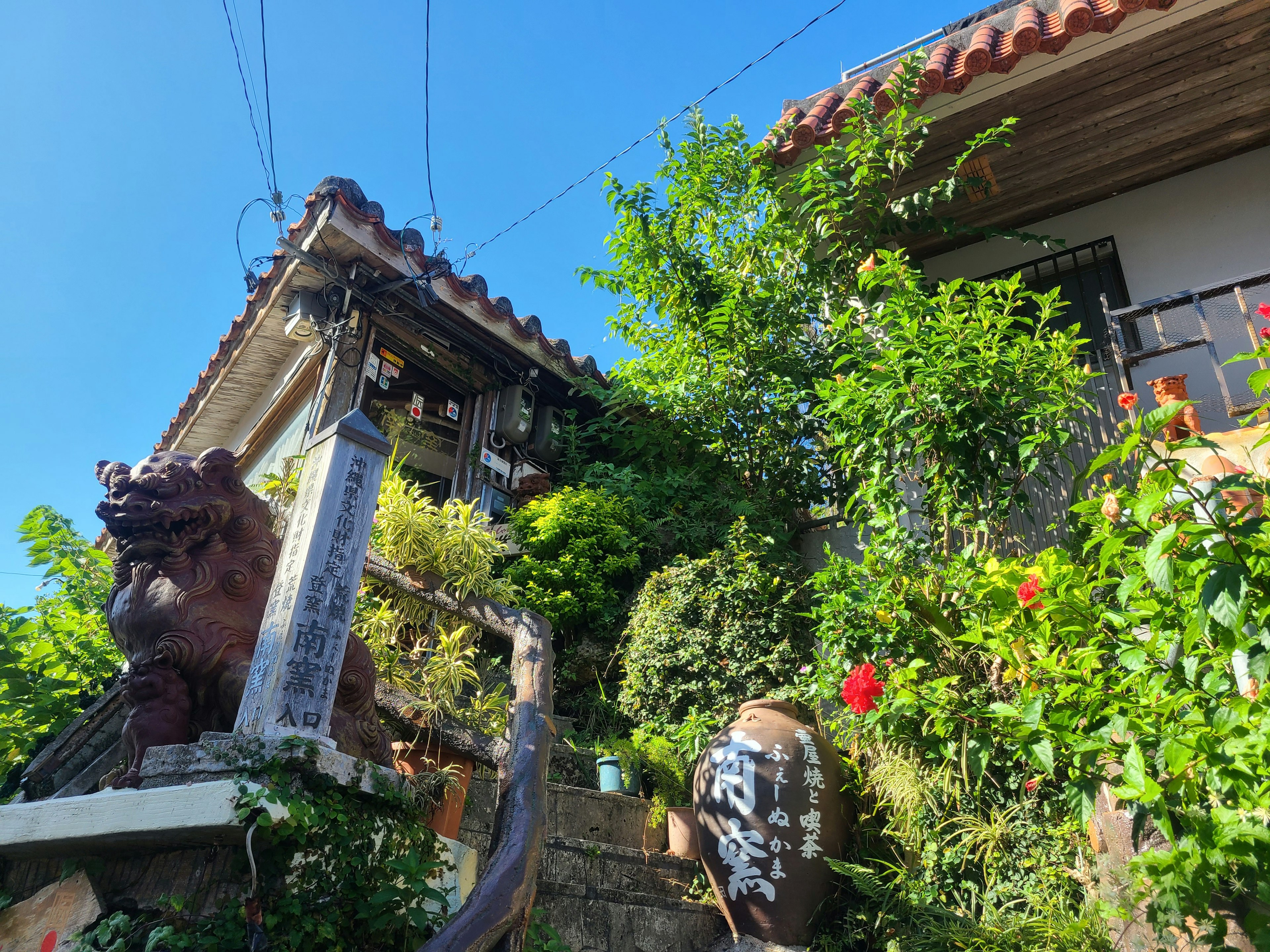 Casa tradicional rodeada de vegetación con escaleras y escultura de león