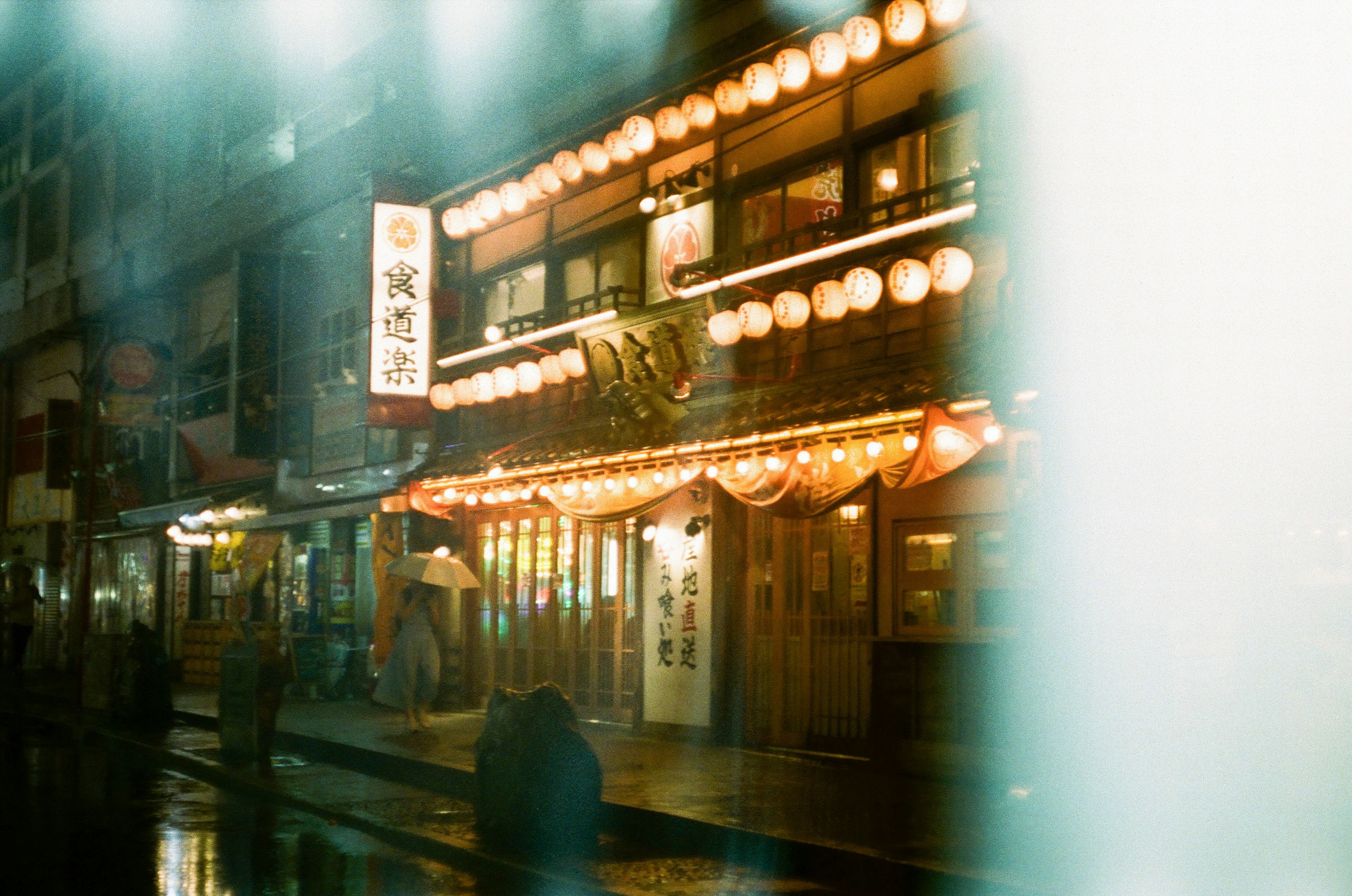 Japanese izakaya illuminated by lanterns in the rain