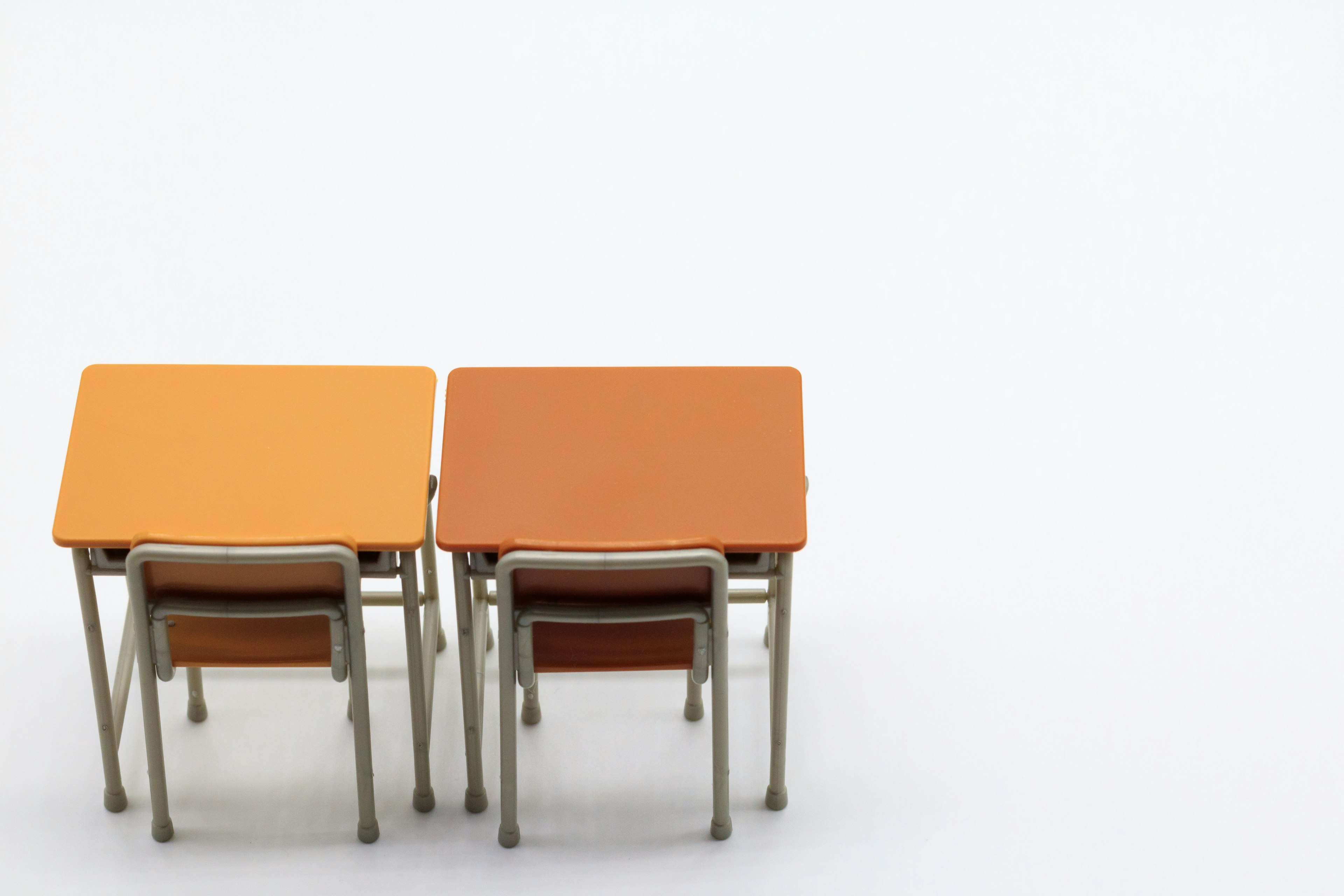 Two orange tables with chairs set against a white background