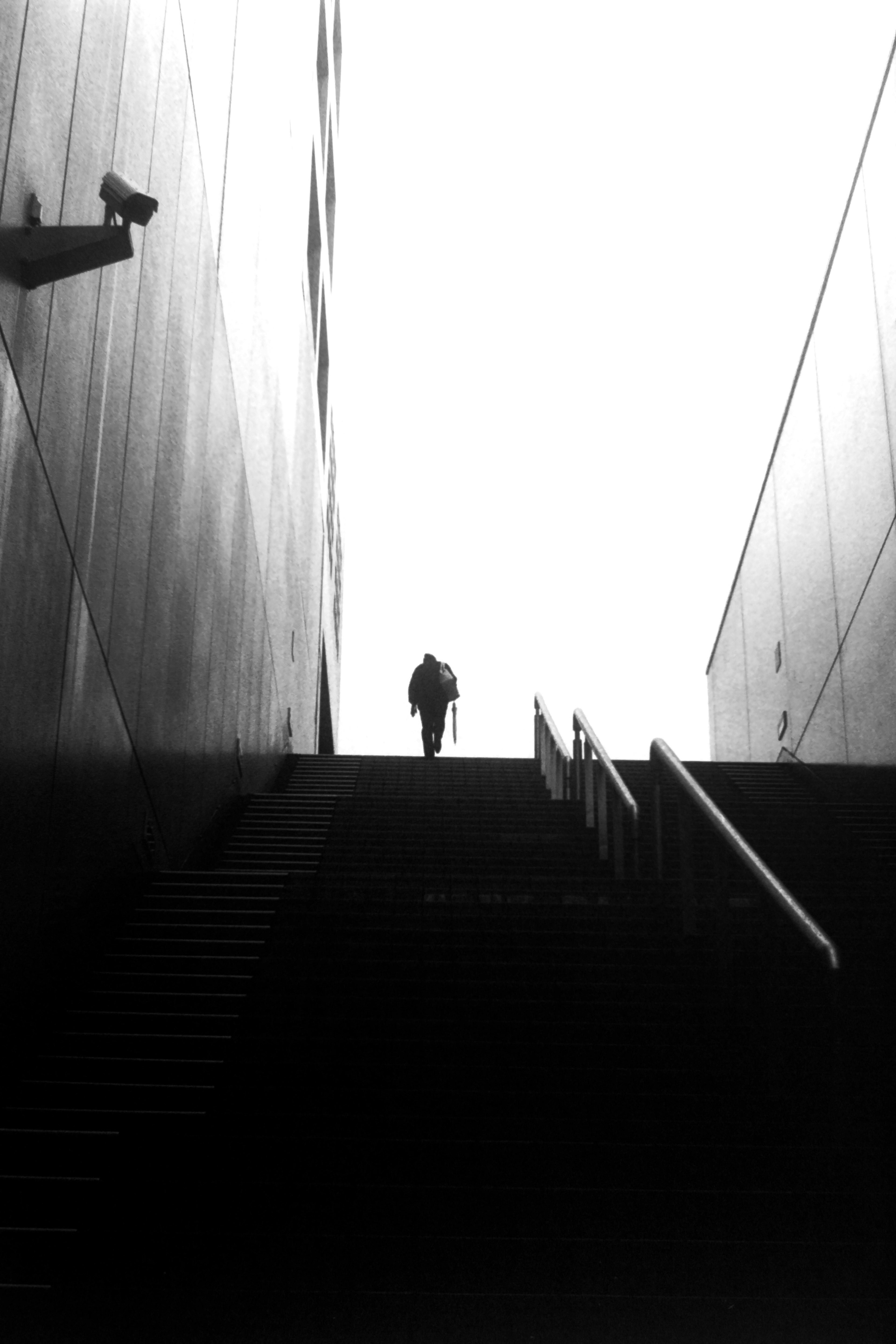 Silhouette of a person ascending stairs against a bright background