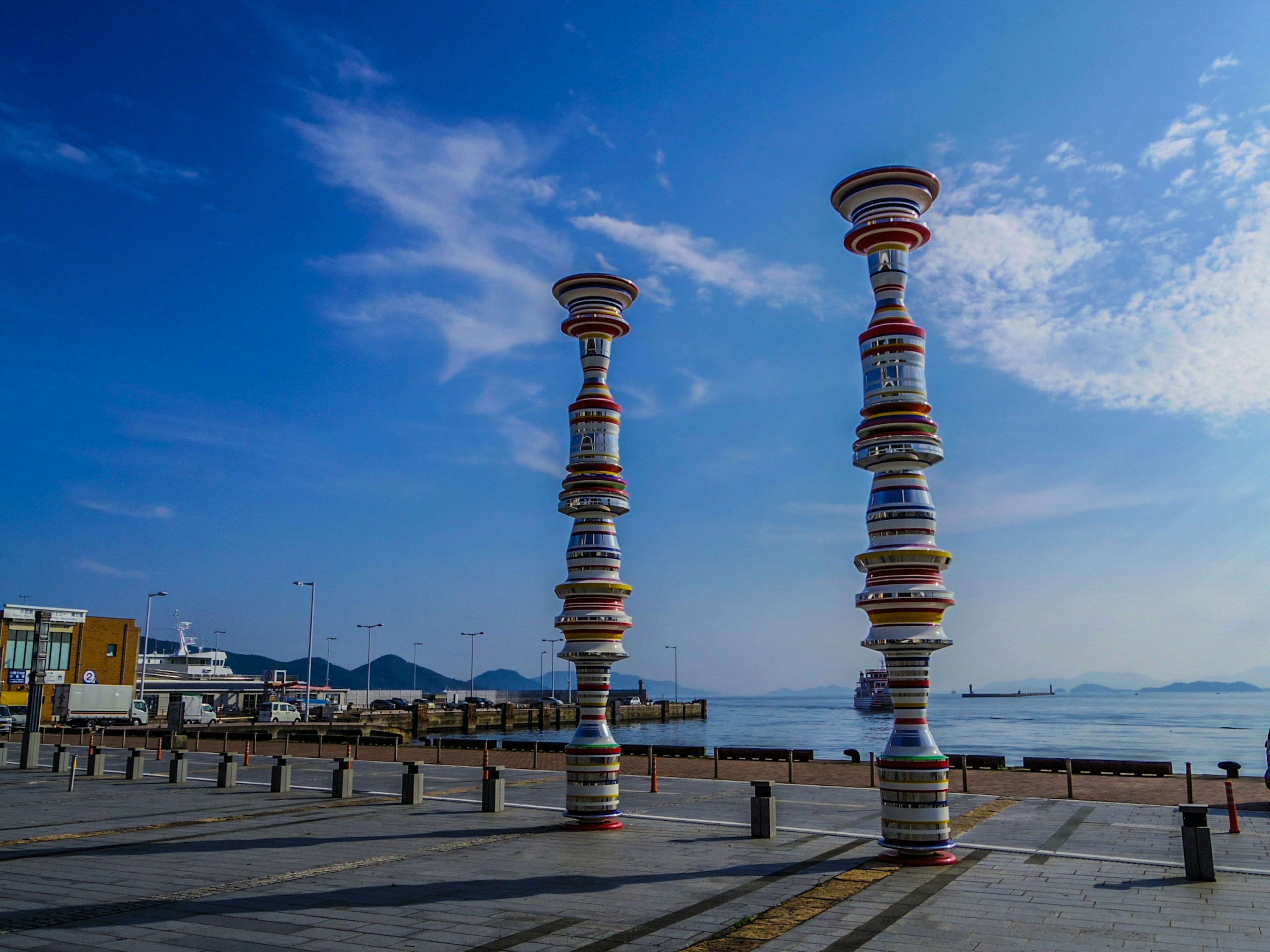 Bunte Skulpturensäulen am Meer mit blauem Himmel