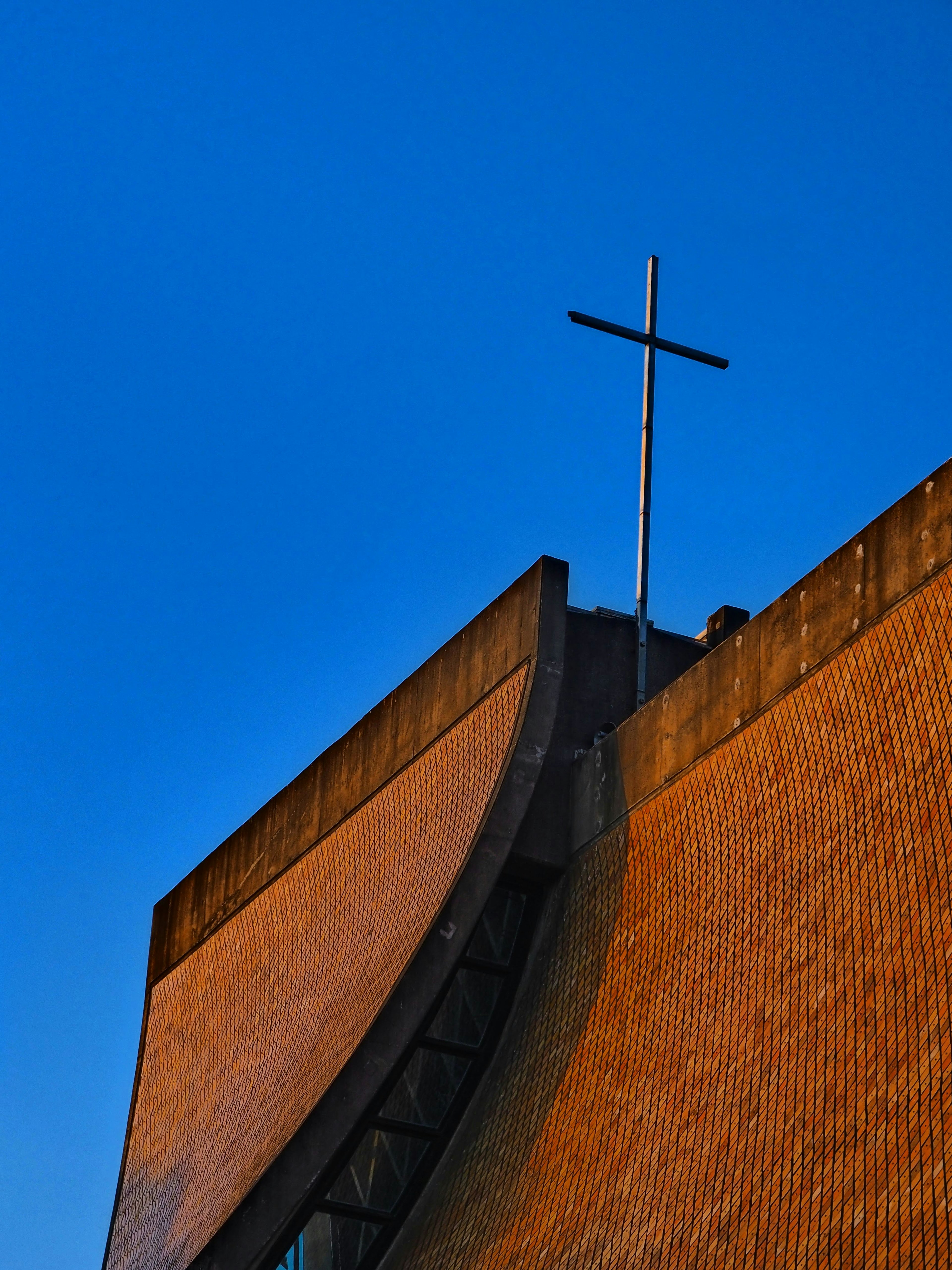 Partie d'un toit d'église avec une croix sous un ciel bleu