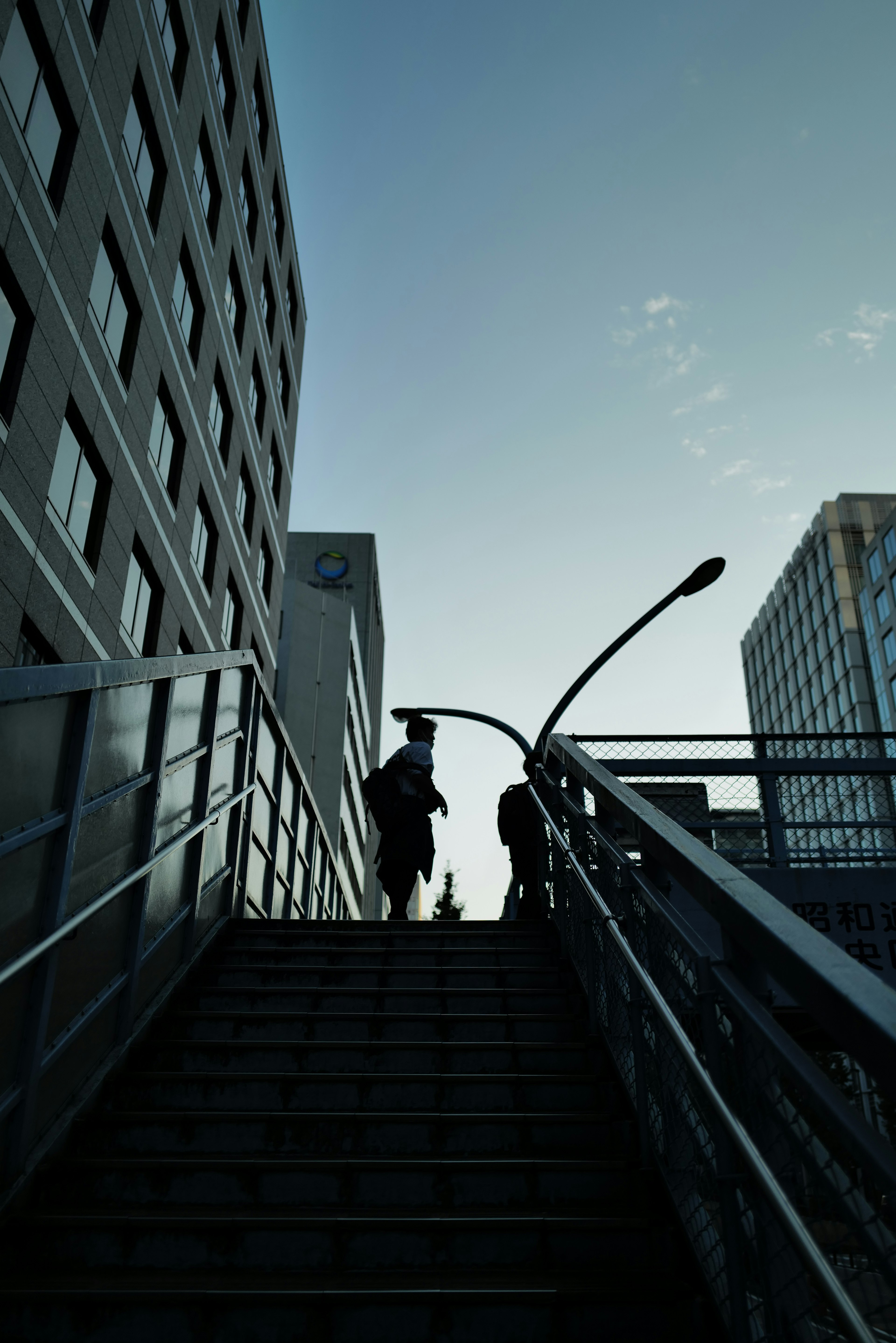 Silhouettes of people climbing stairs between buildings