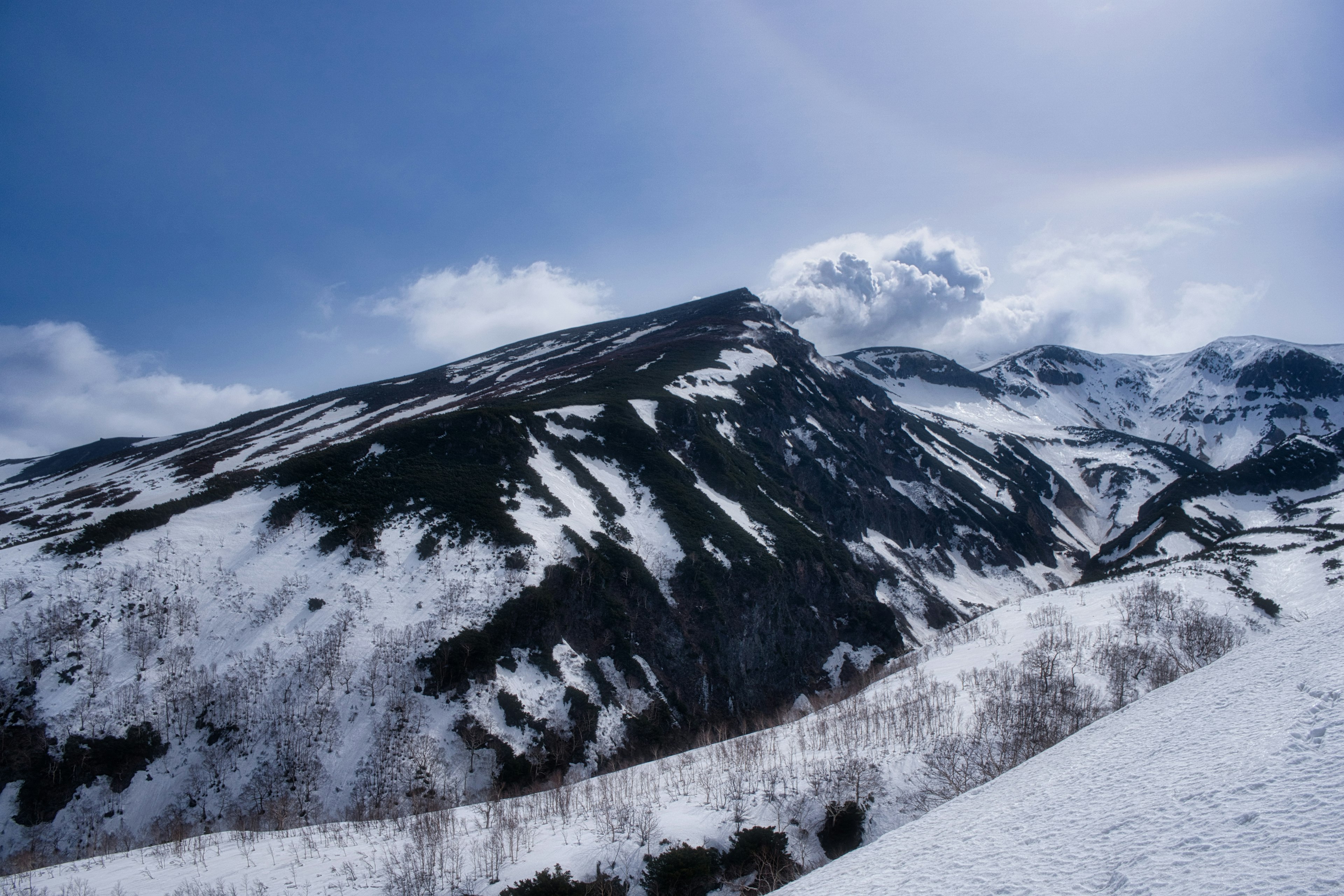 Paisaje montañoso cubierto de nieve bajo un cielo azul