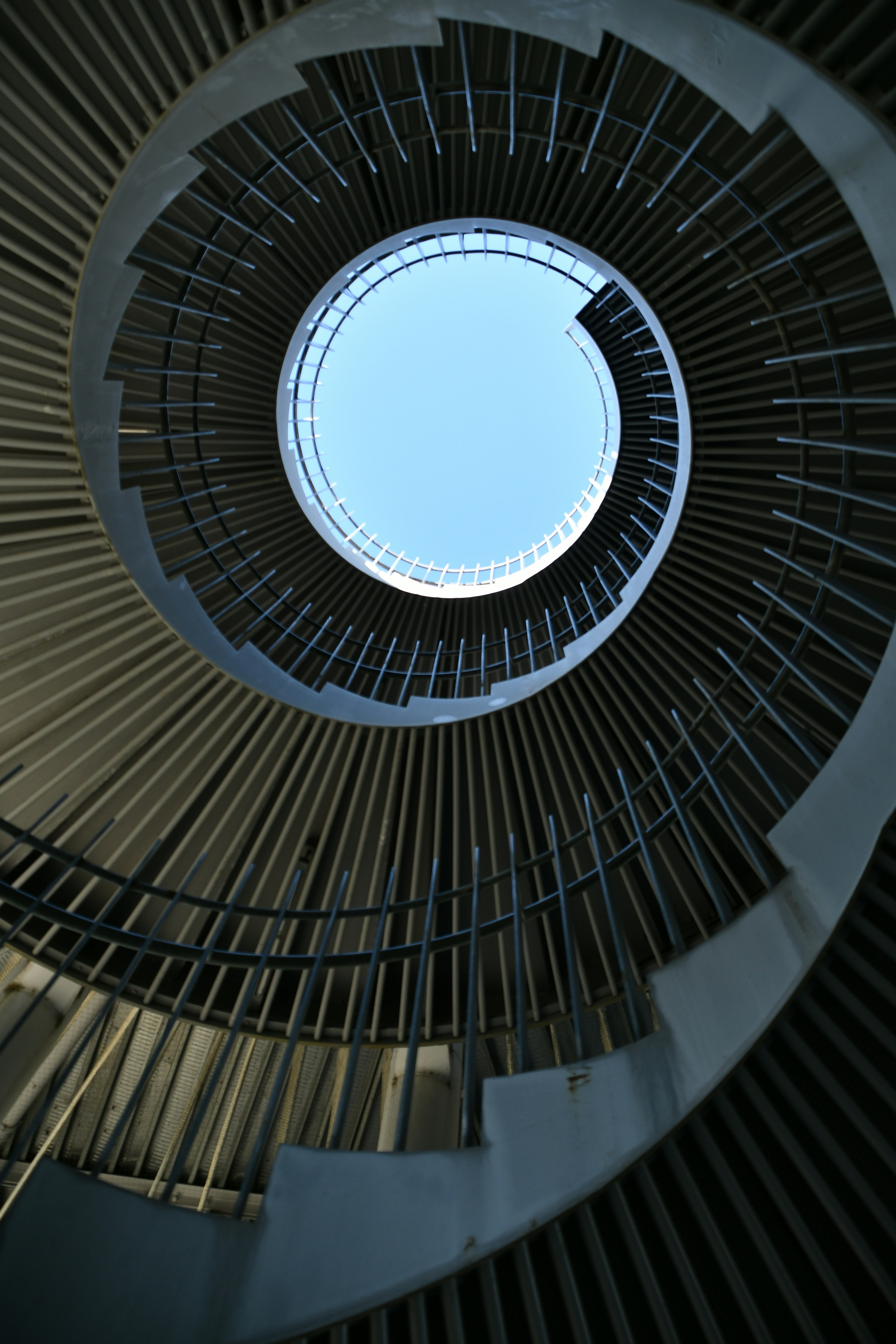 View looking up a spiral staircase revealing a blue sky