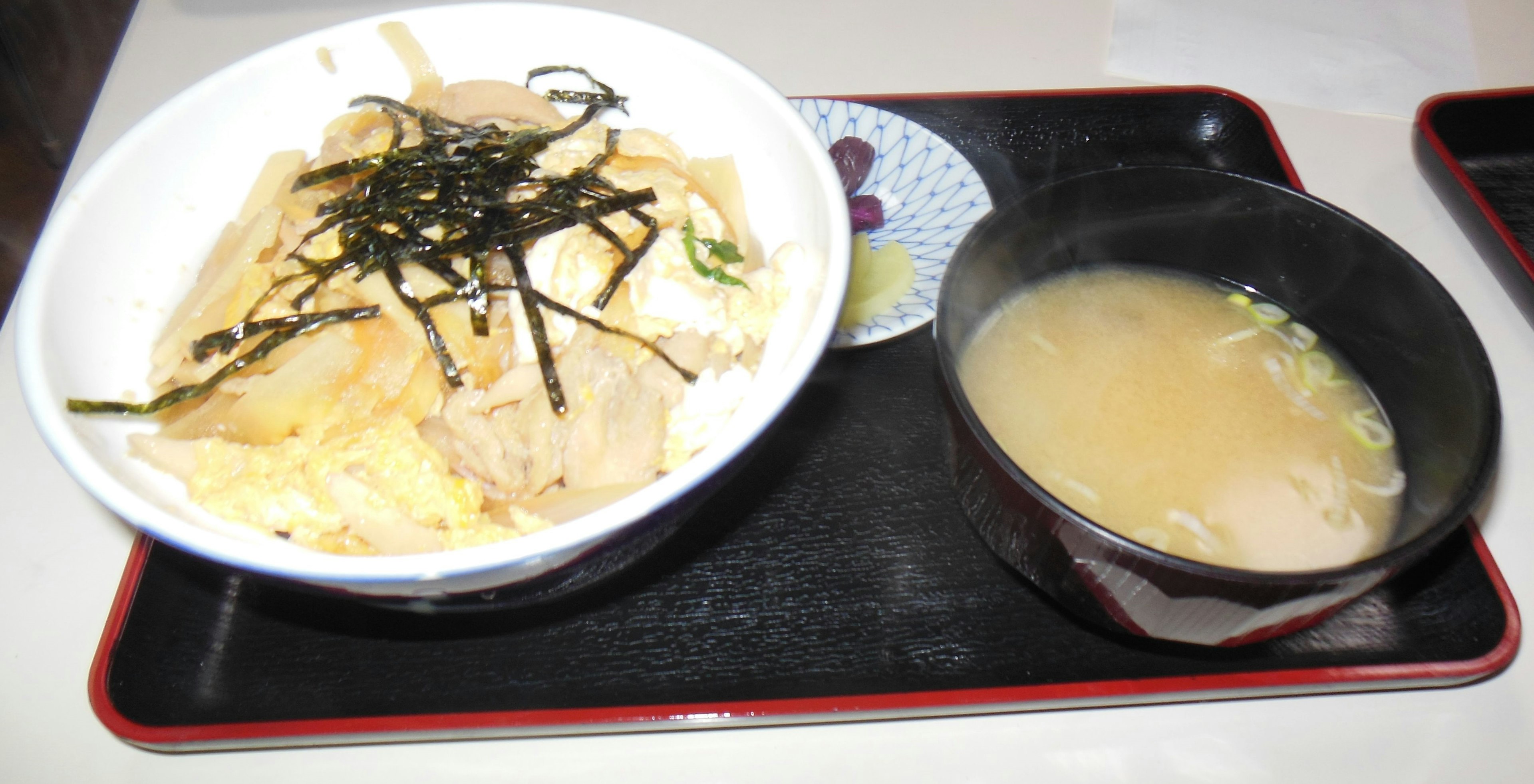 Rice bowl topped with seaweed served with a side of miso soup