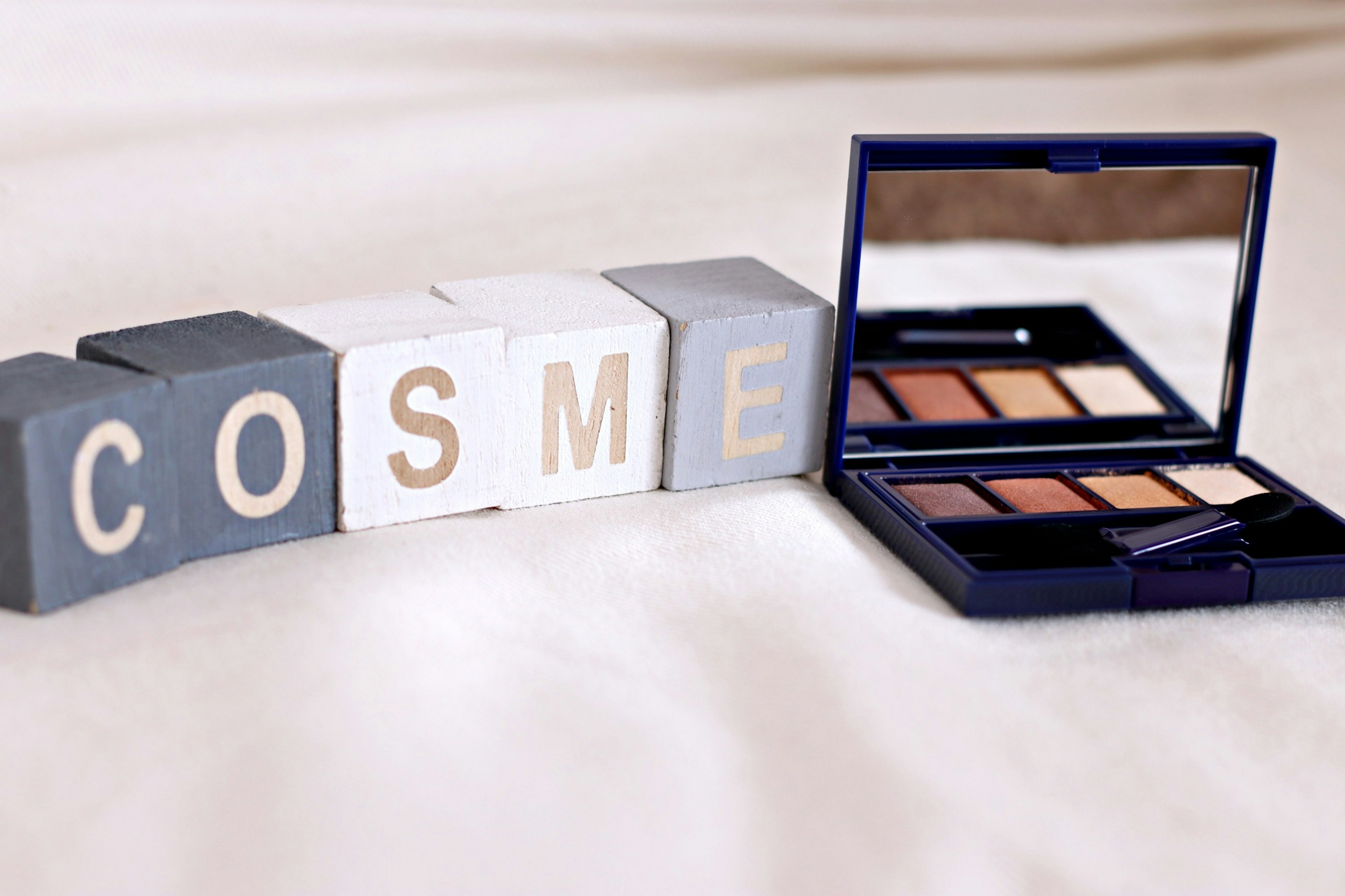 Cosmetic palette next to blocks spelling COSME