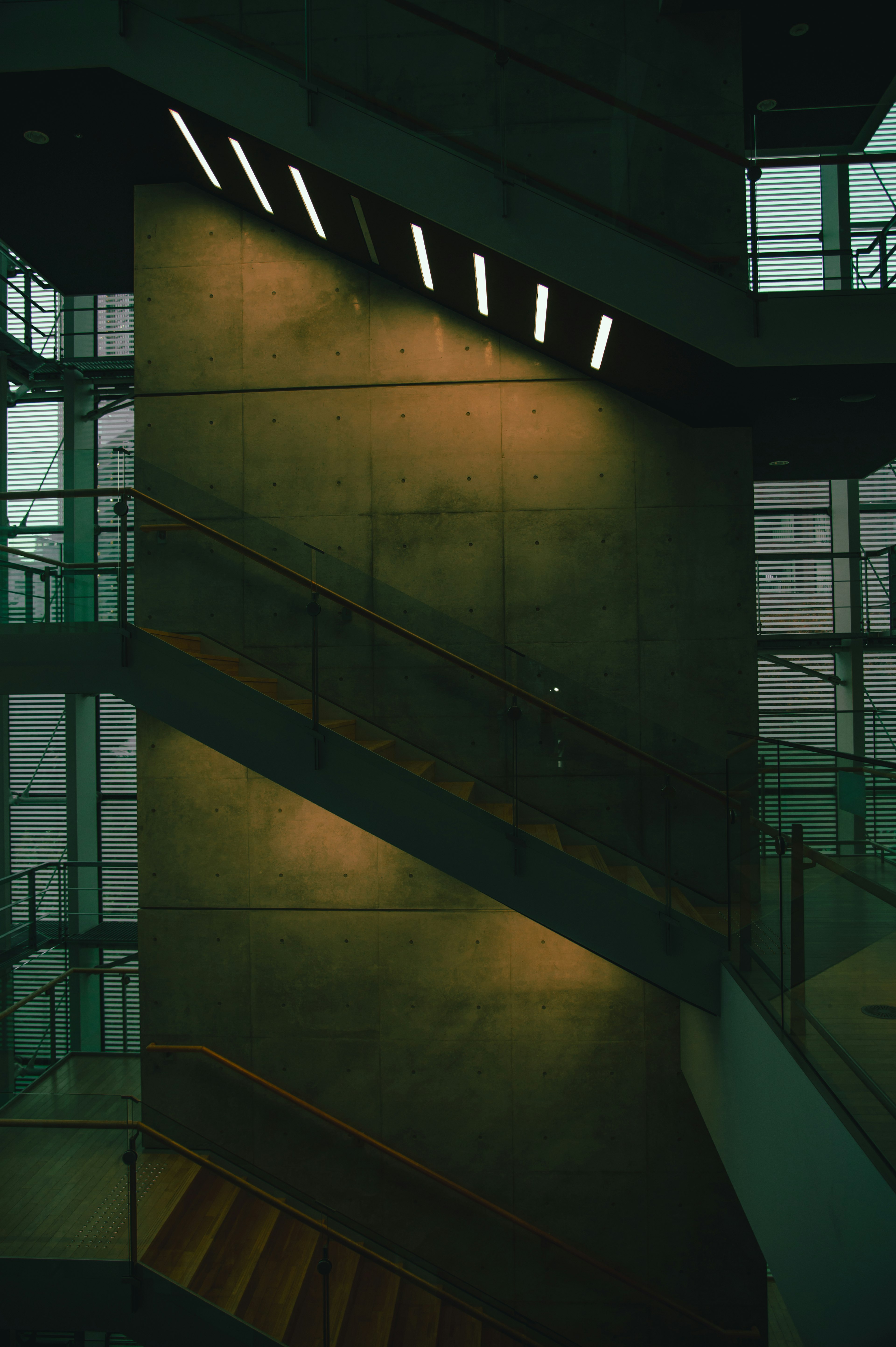 Interior de un edificio moderno con una escalera y una pared de concreto en un ambiente oscuro