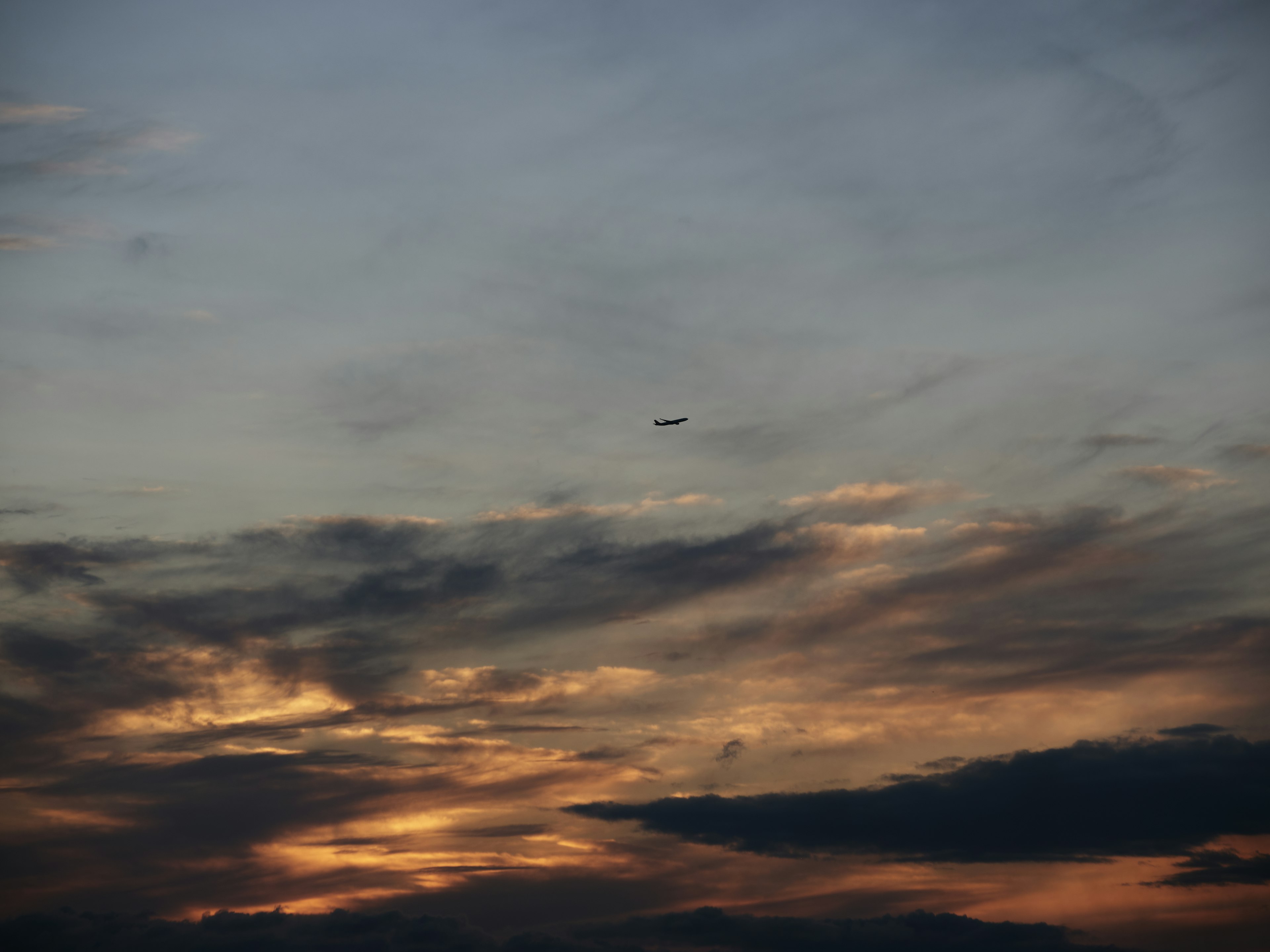 夕焼けの空に浮かぶ飛行機と色彩豊かな雲