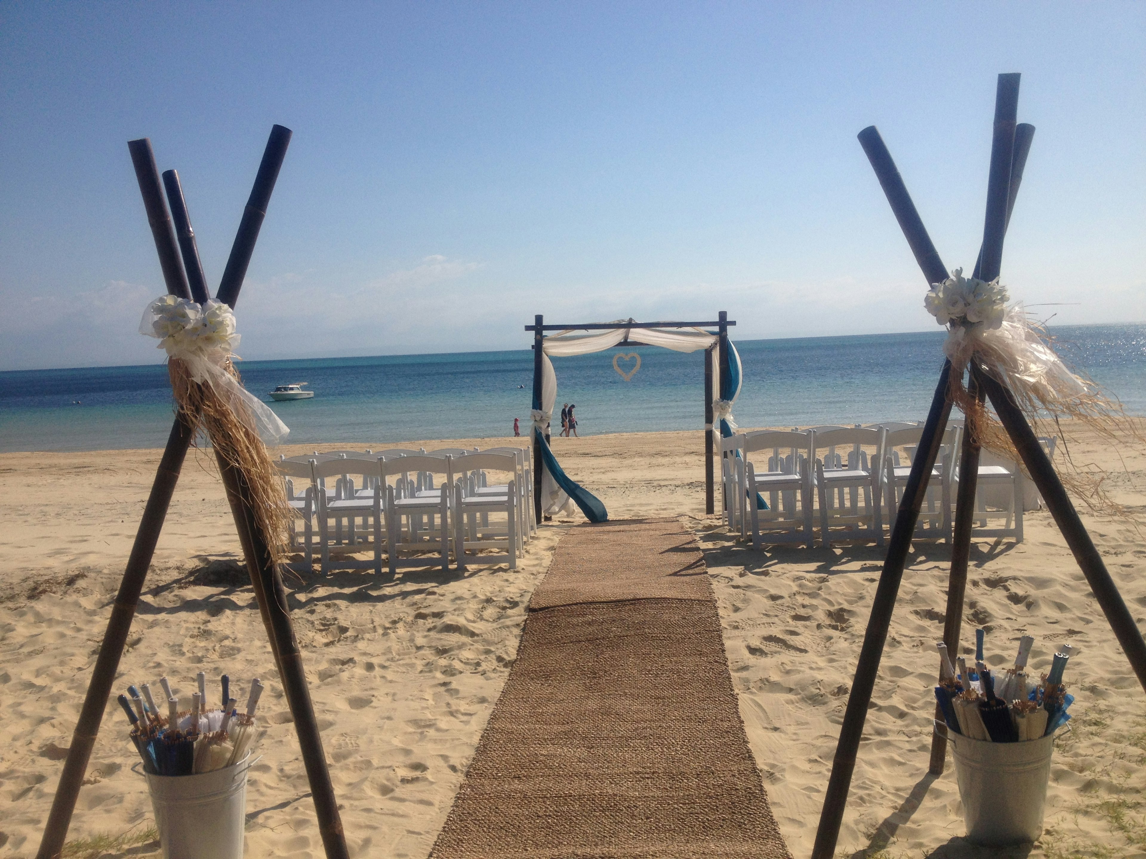 Configuración de boda en la playa con sillas blancas y un océano azul