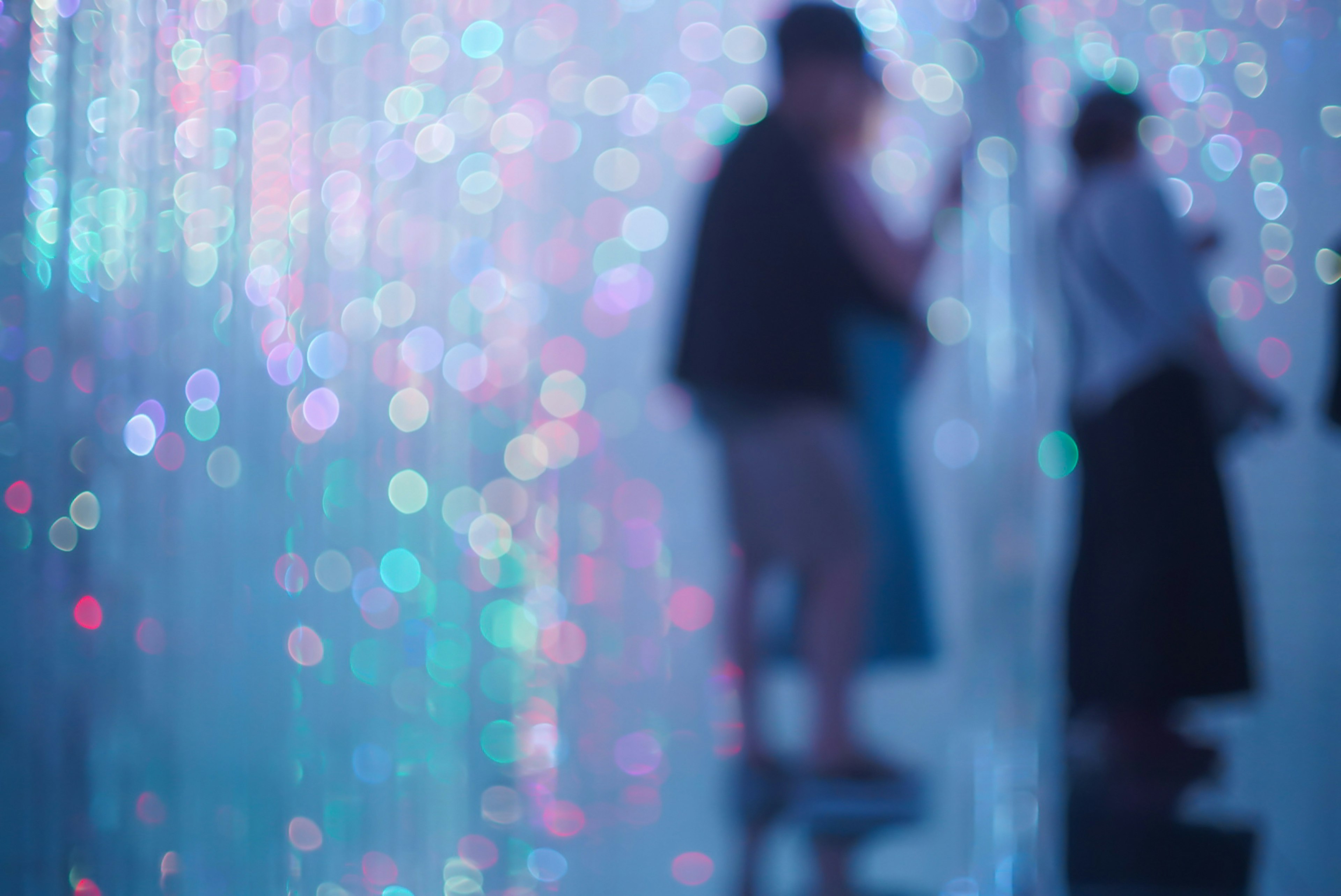 Siluetas de personas de pie contra un fondo borroso de luces coloridas