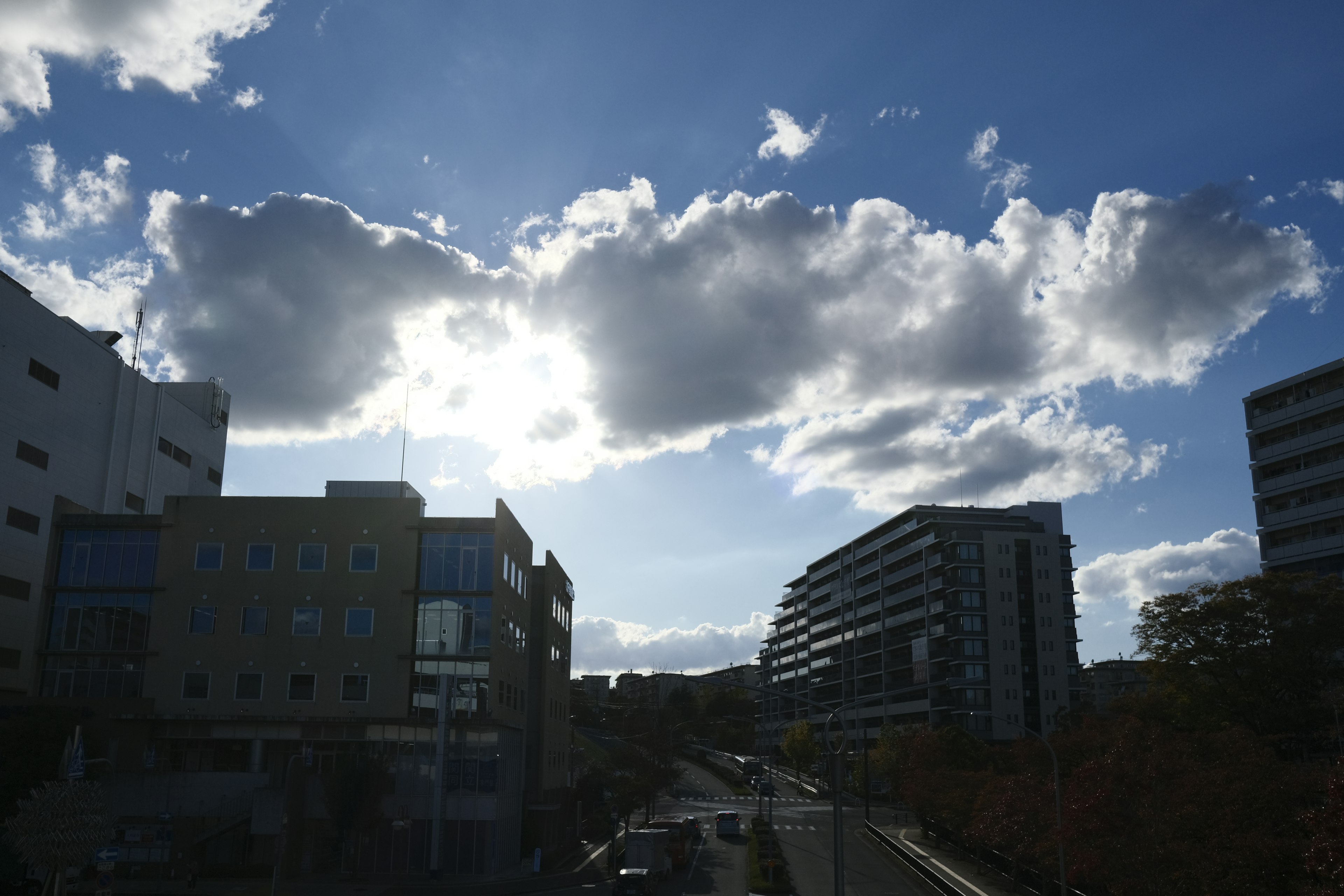 Paesaggio urbano con cielo blu e nuvole che presenta edifici e una strada