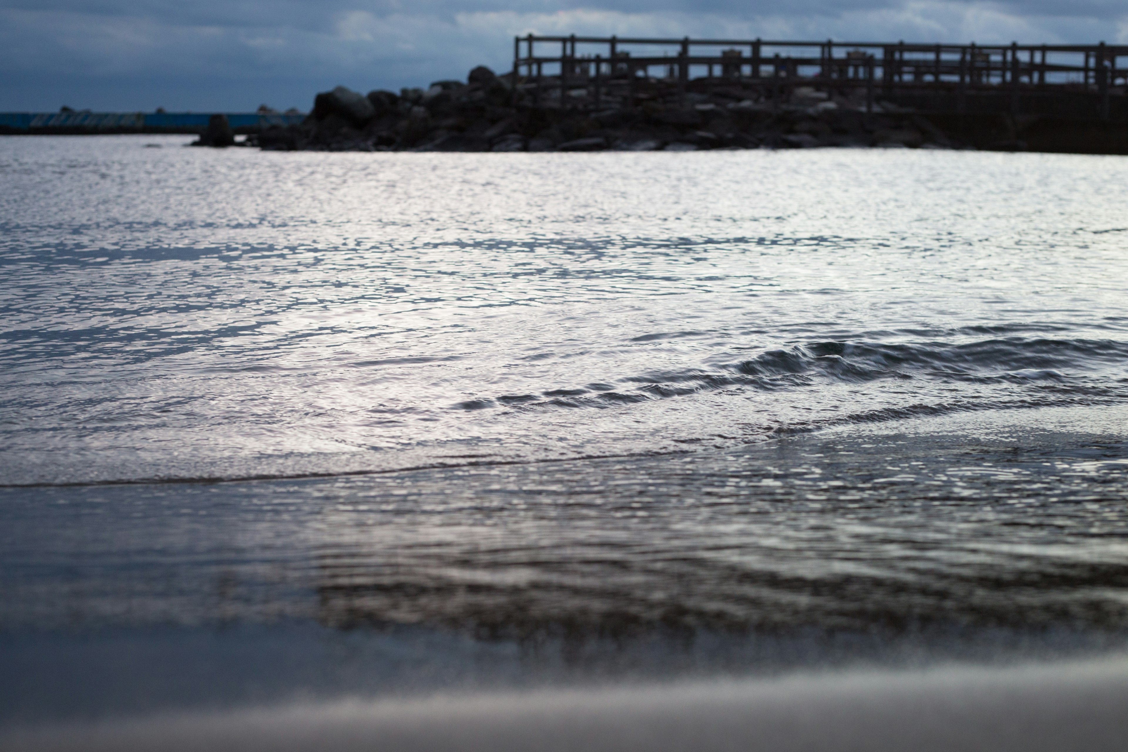 Superficie del mar tranquila reflejando luz con estructuras distantes