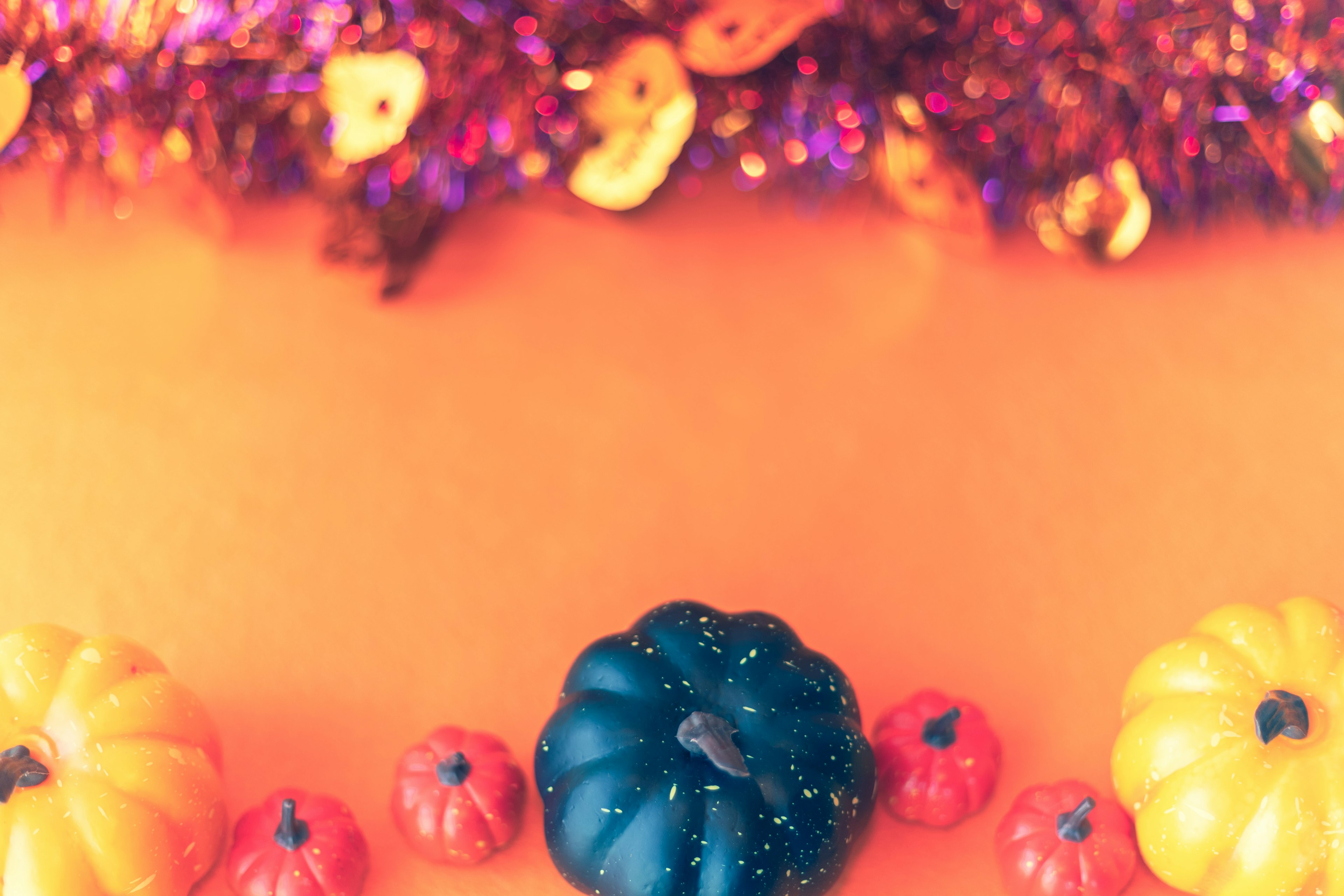 Calabazas coloridas y decoraciones brillantes sobre un fondo naranja