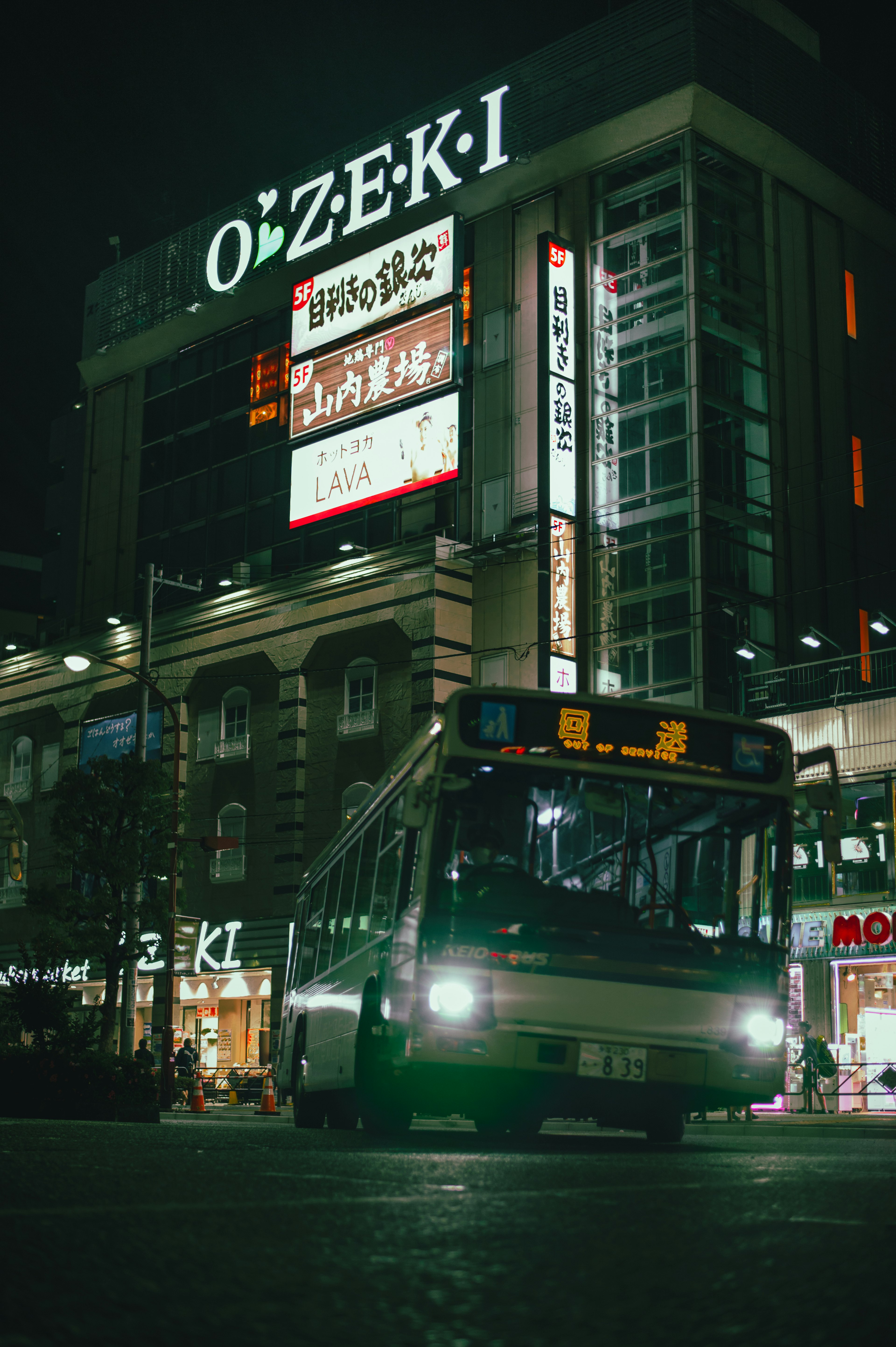 Bus yang berhenti di depan tanda OZEKI di malam hari