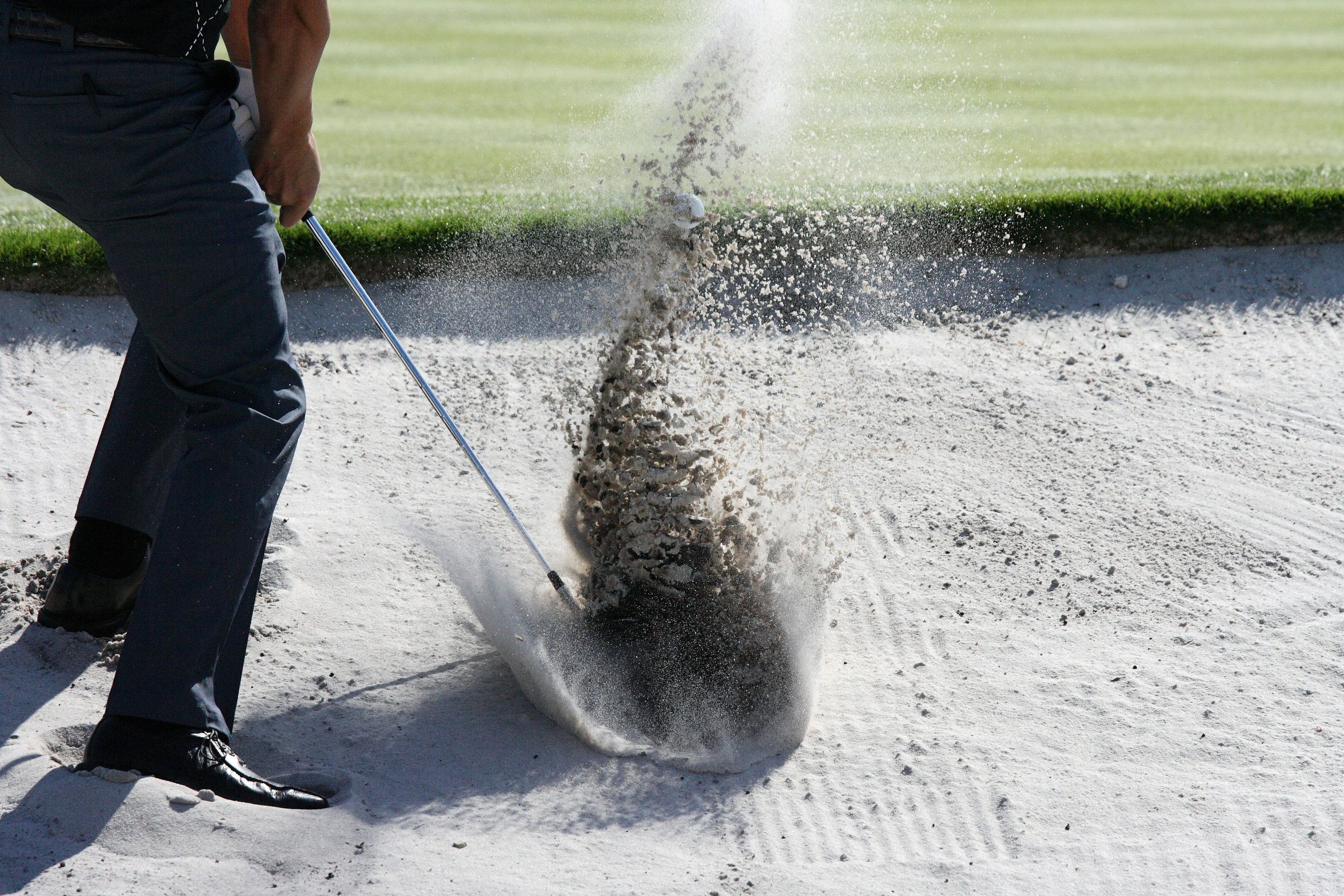 Primo piano di un golfista che colpisce una palla da un bunker di sabbia