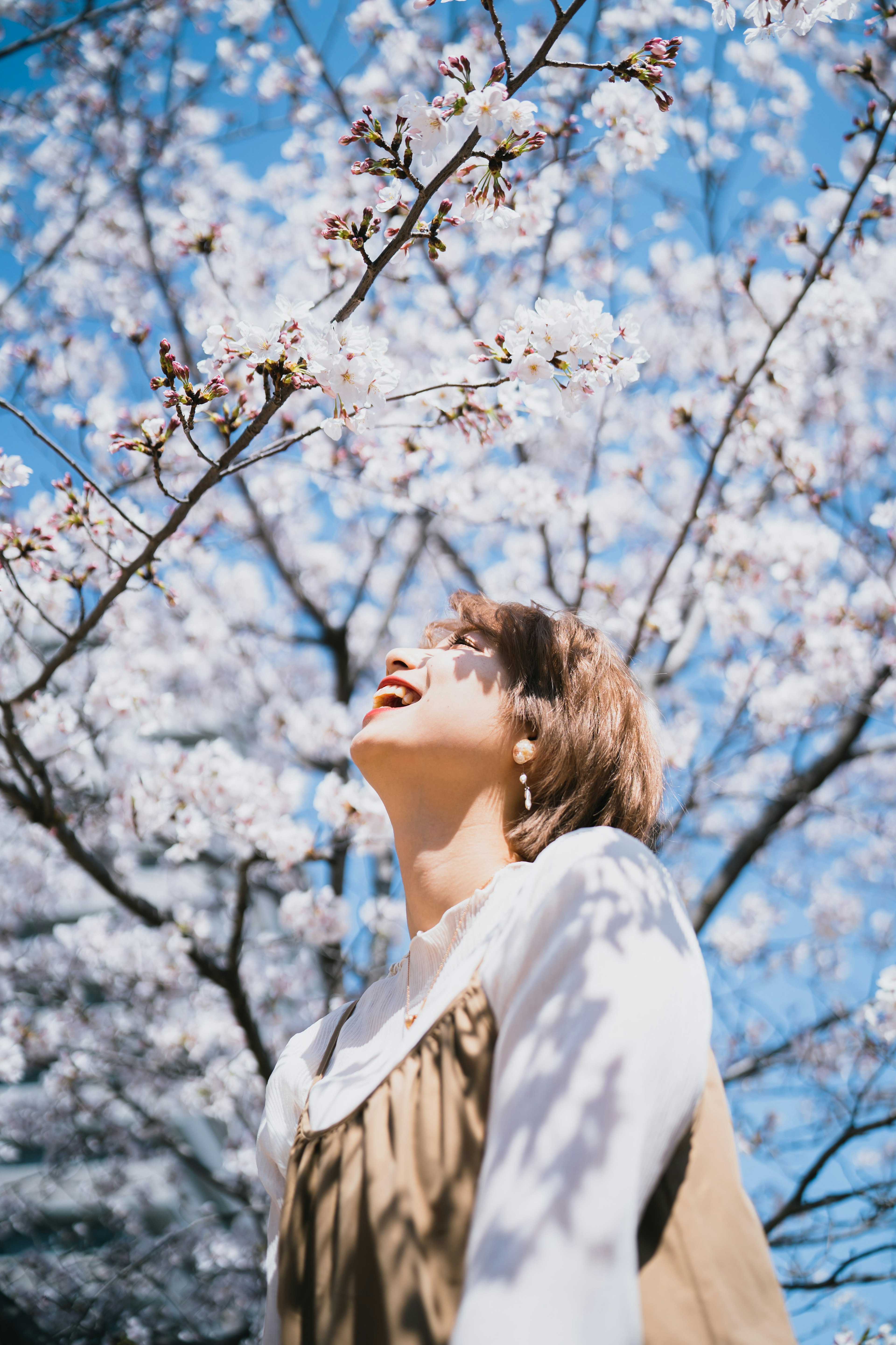 桜の花の下で笑顔の女性