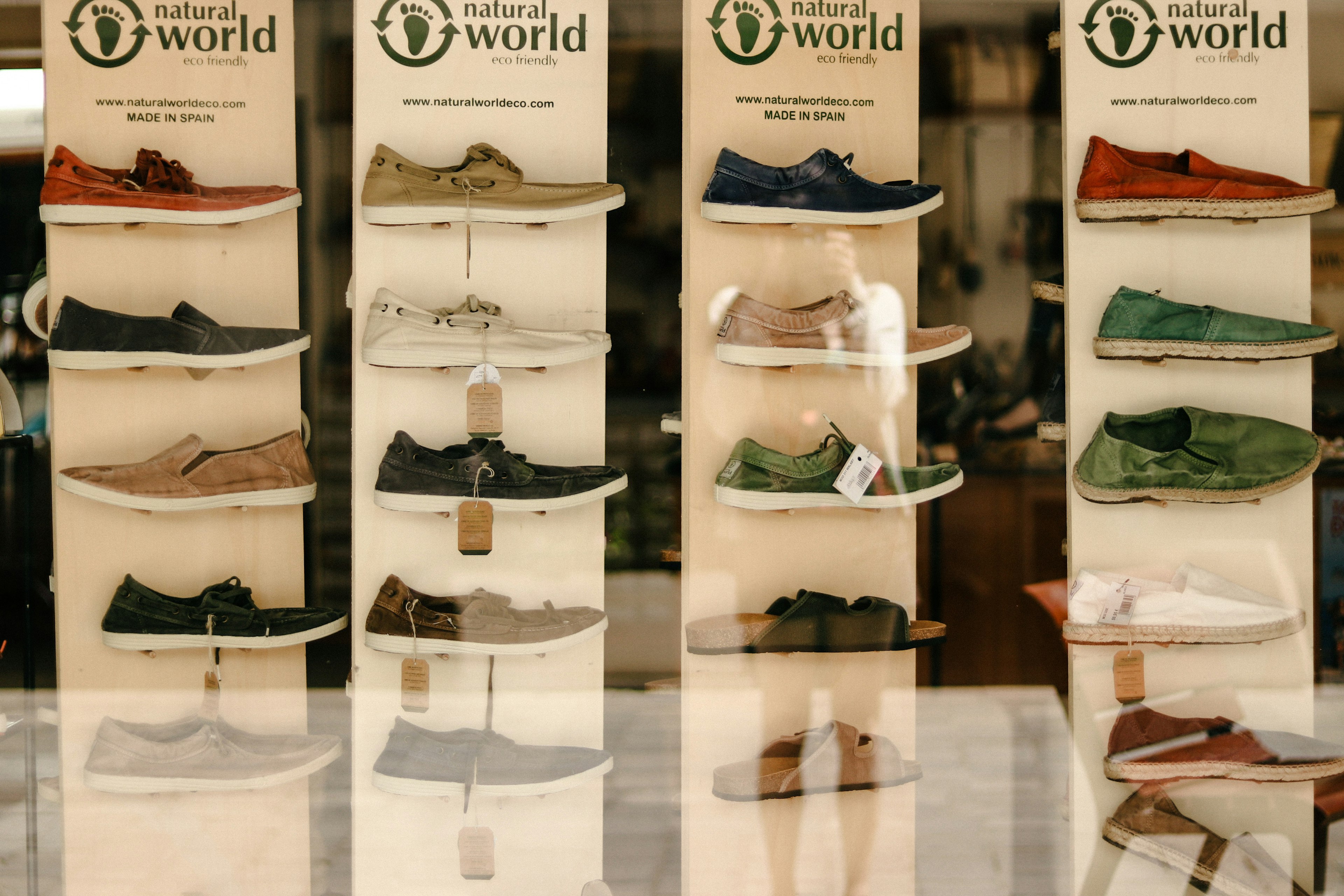 Display of various shoes in a store featuring the Natural World brand