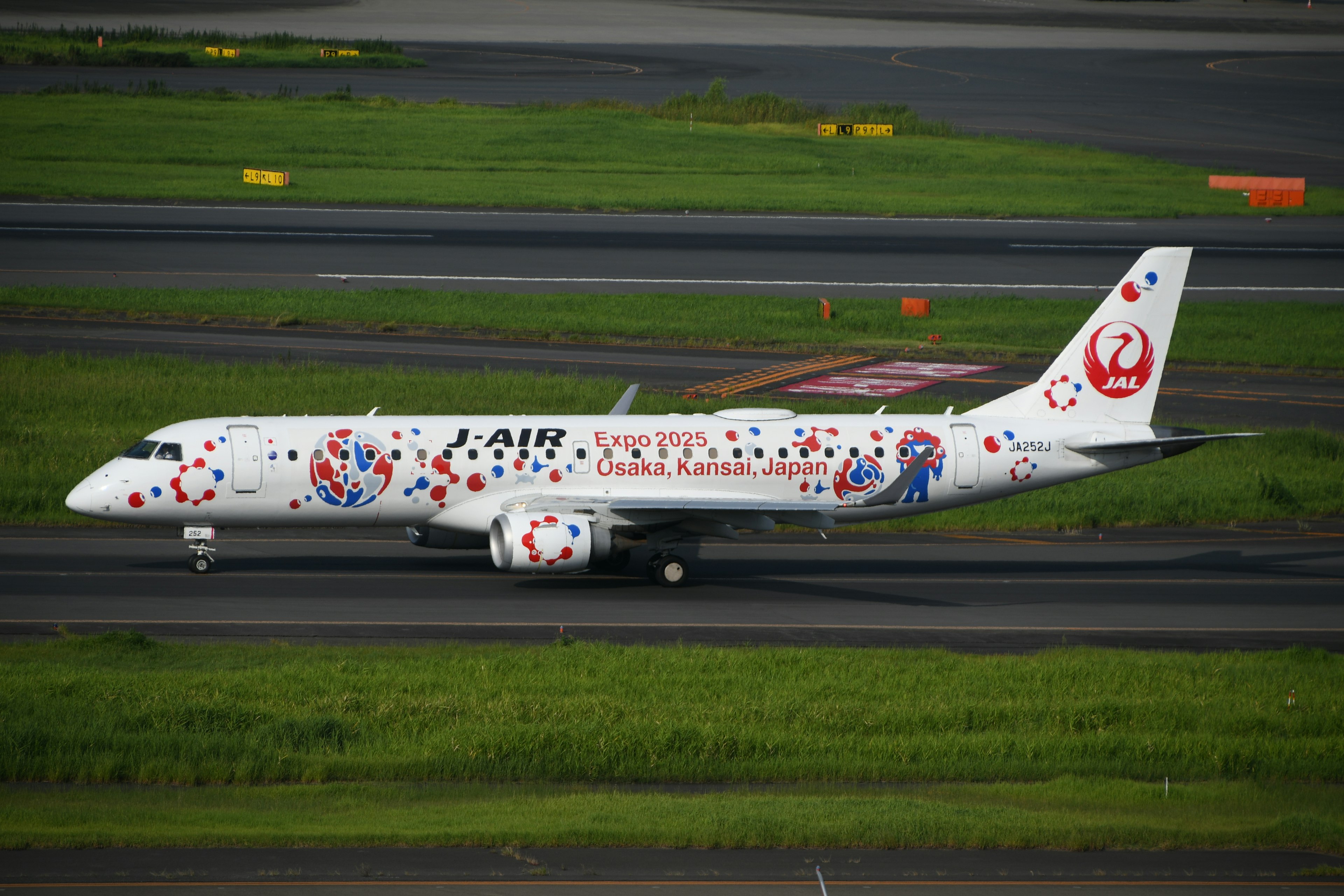 An airplane with a white body decorated with colorful patterns taxiing on the runway