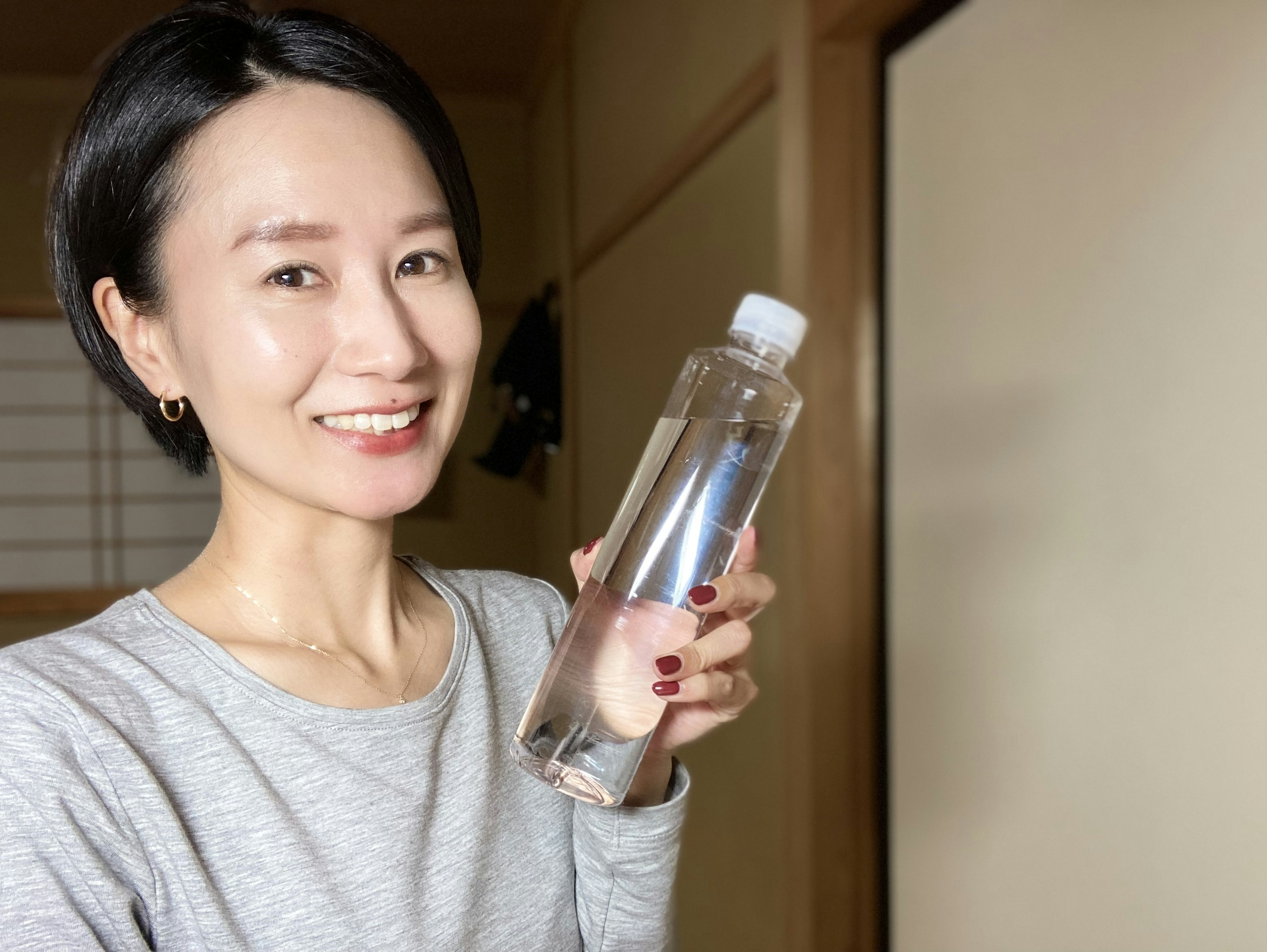 Donna sorridente che tiene una bottiglia d'acqua trasparente