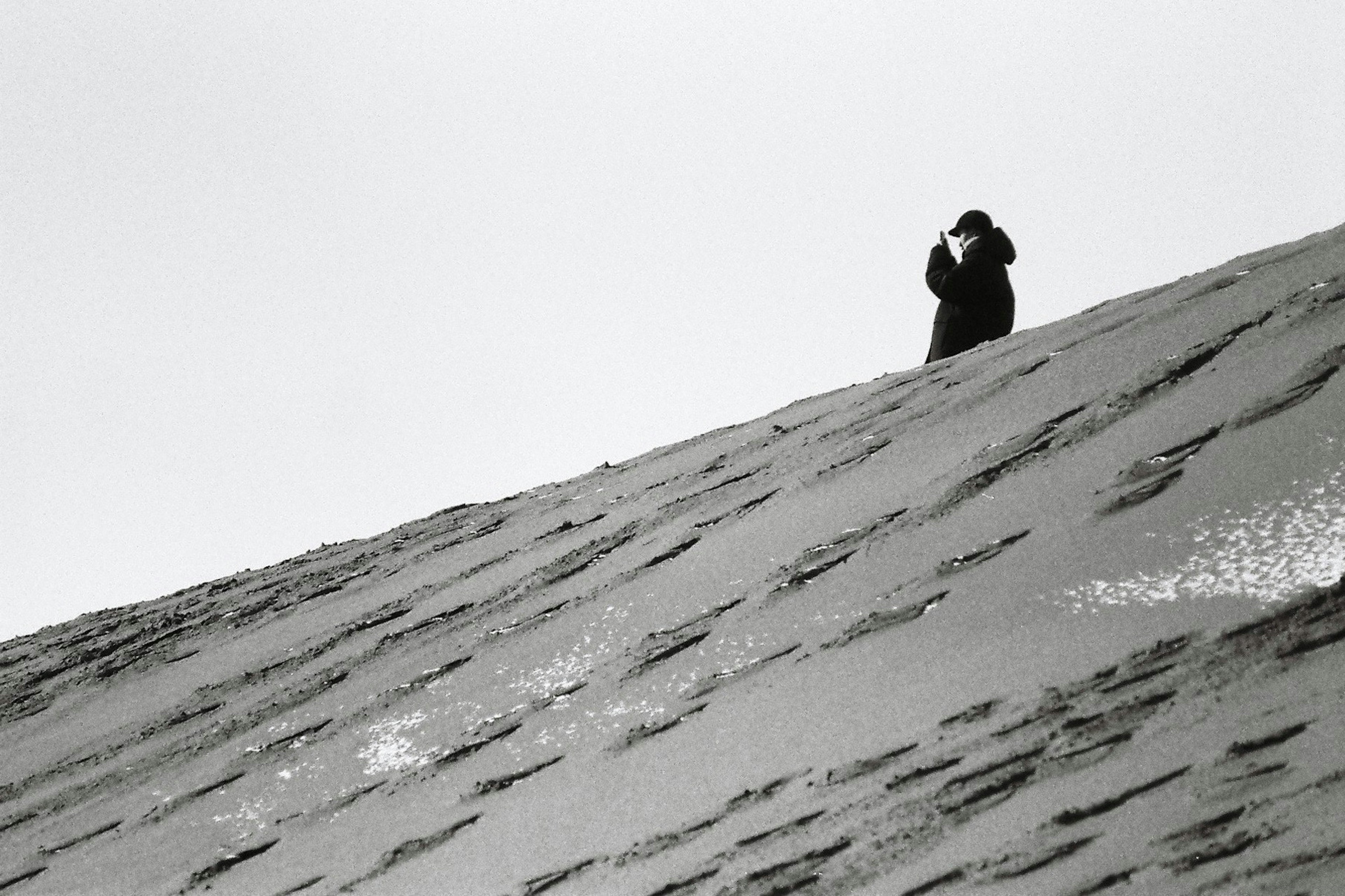 Eine Person steht auf einem verschneiten Hang und hebt die Hand in einem Schwarz-Weiß-Foto