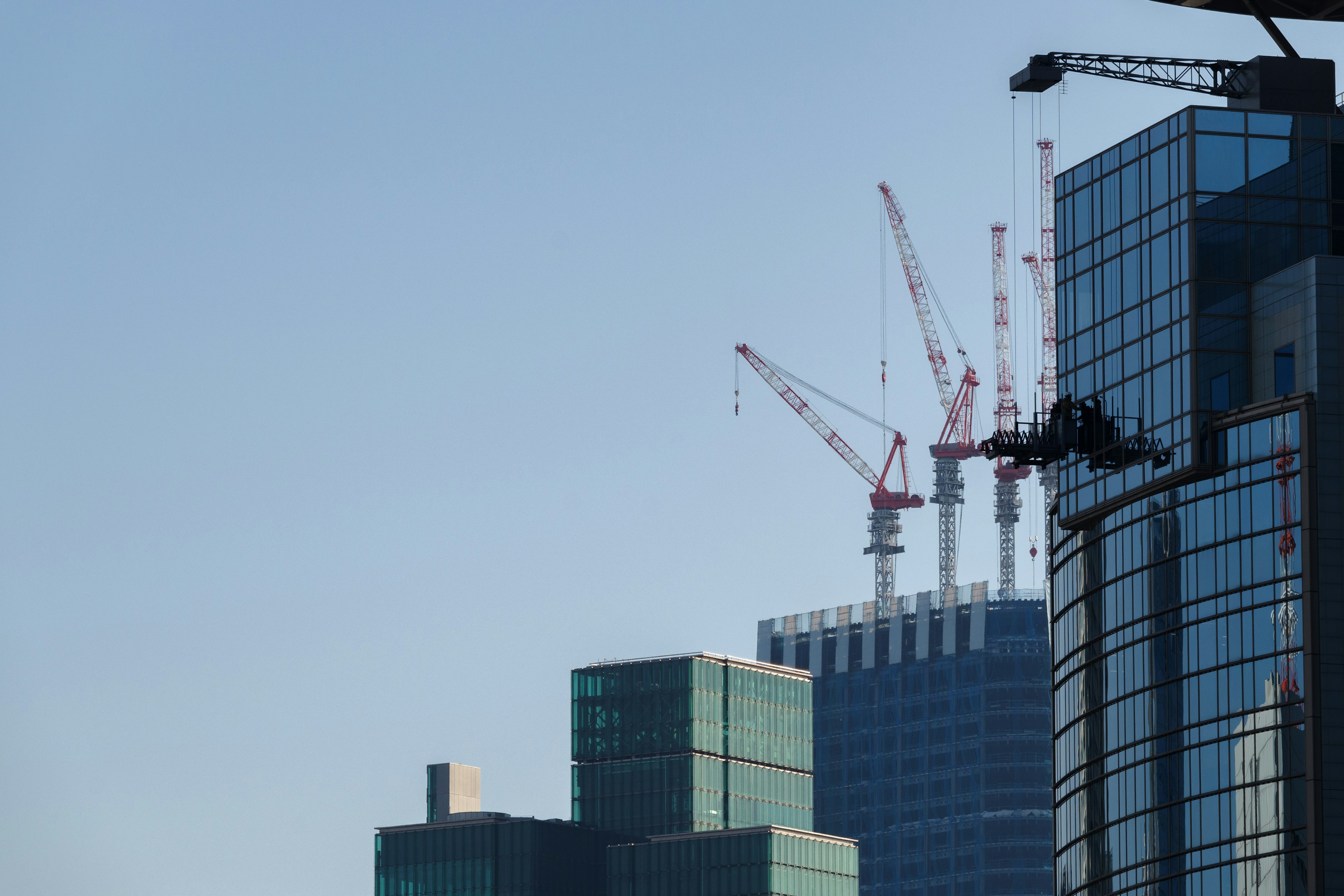 Grúas en la cima de rascacielos modernos contra un cielo azul claro