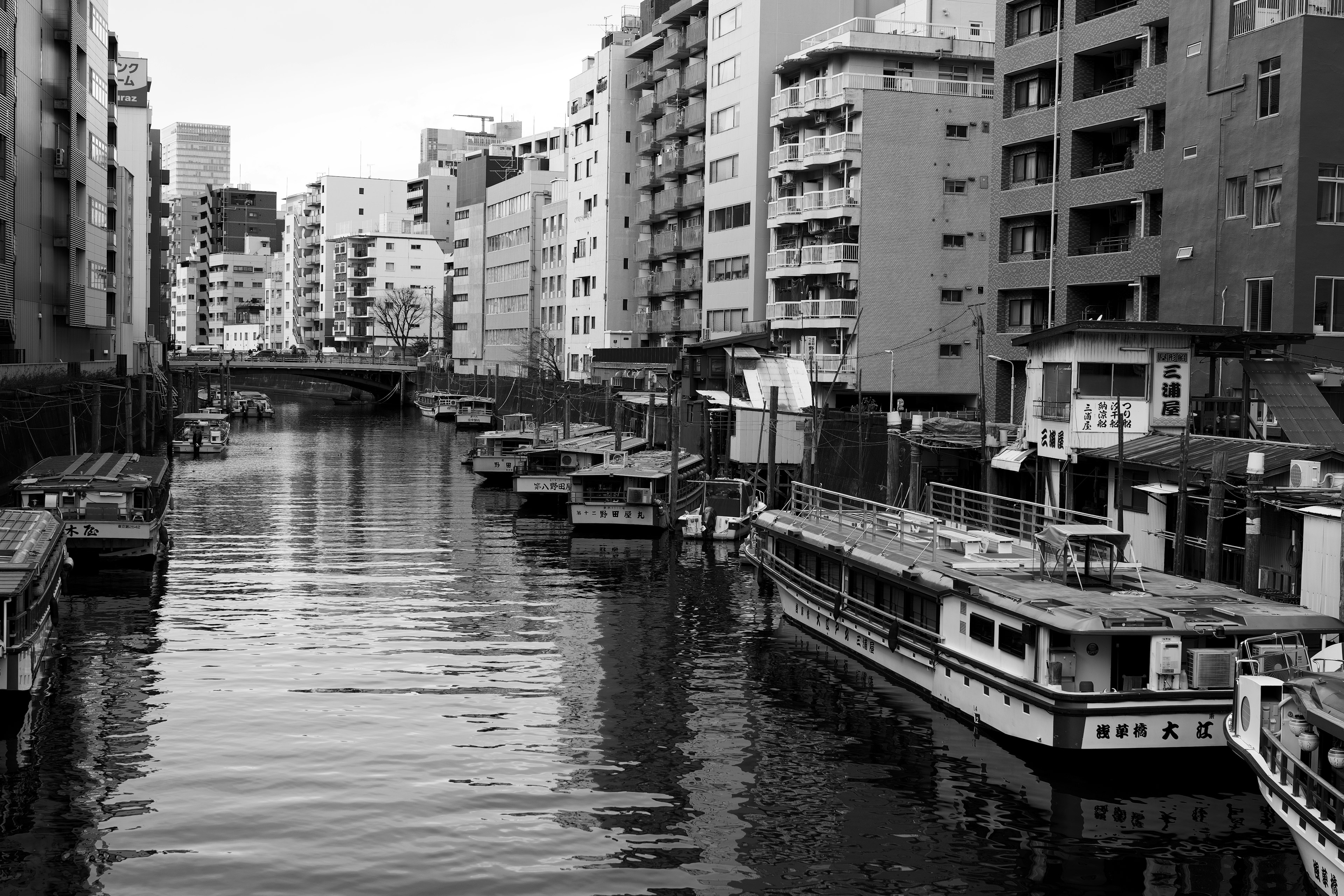 Schwarz-Weiß-Blick auf Boote, die in einem Kanal mit umliegenden Gebäuden festgemacht sind