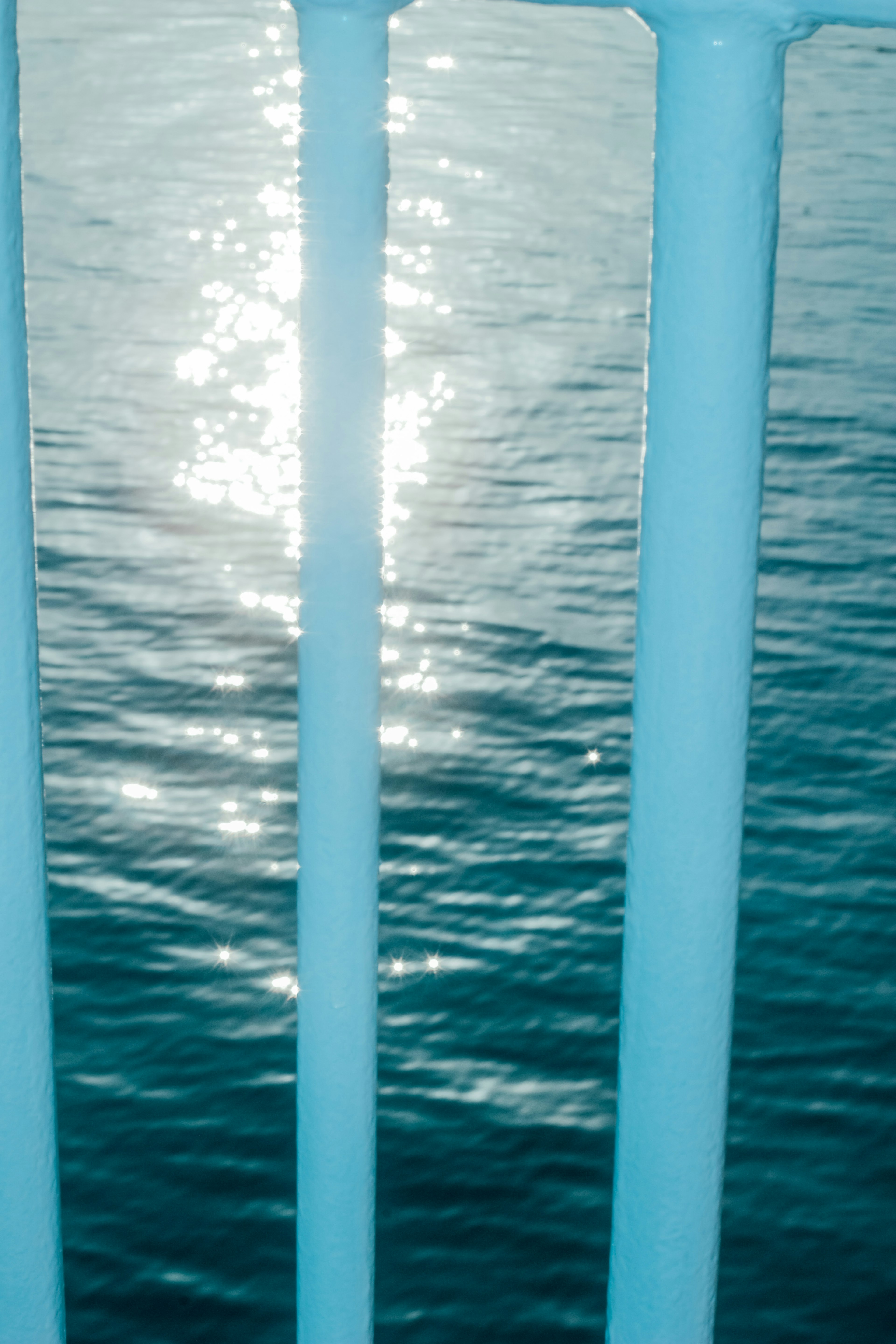 Shimmering water surface viewed through blue railing