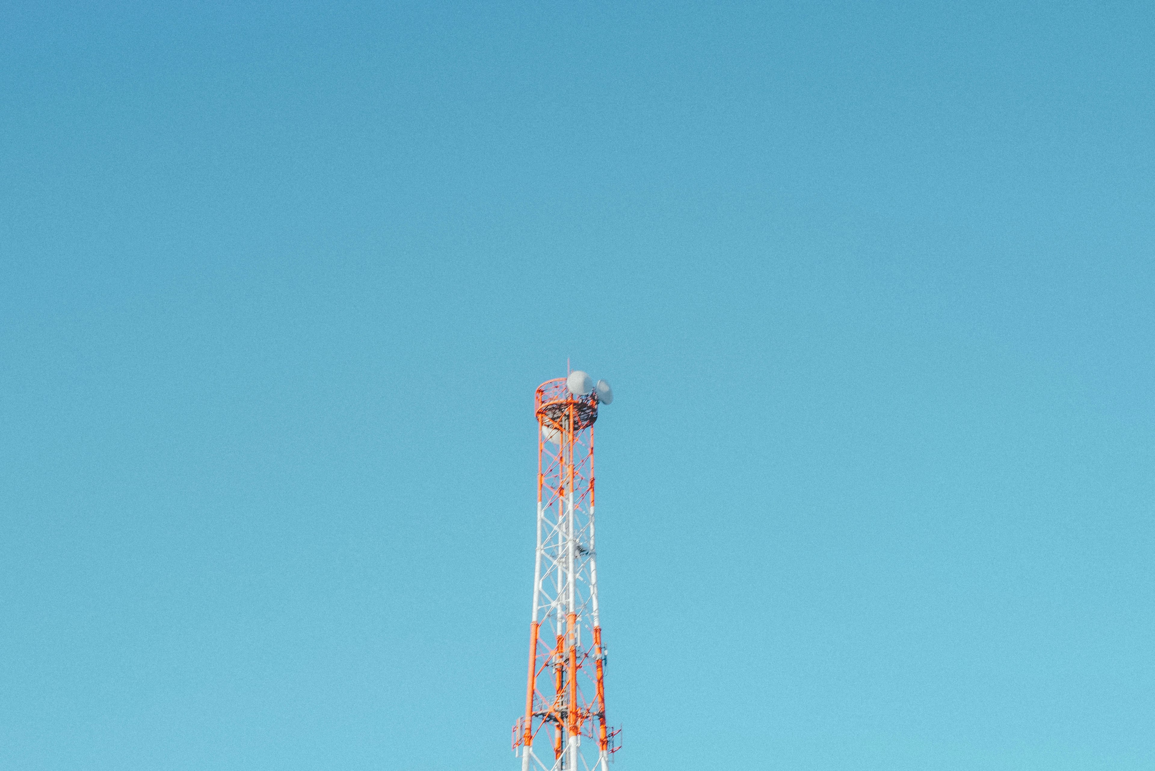 Torre de comunicación roja y blanca contra un cielo azul