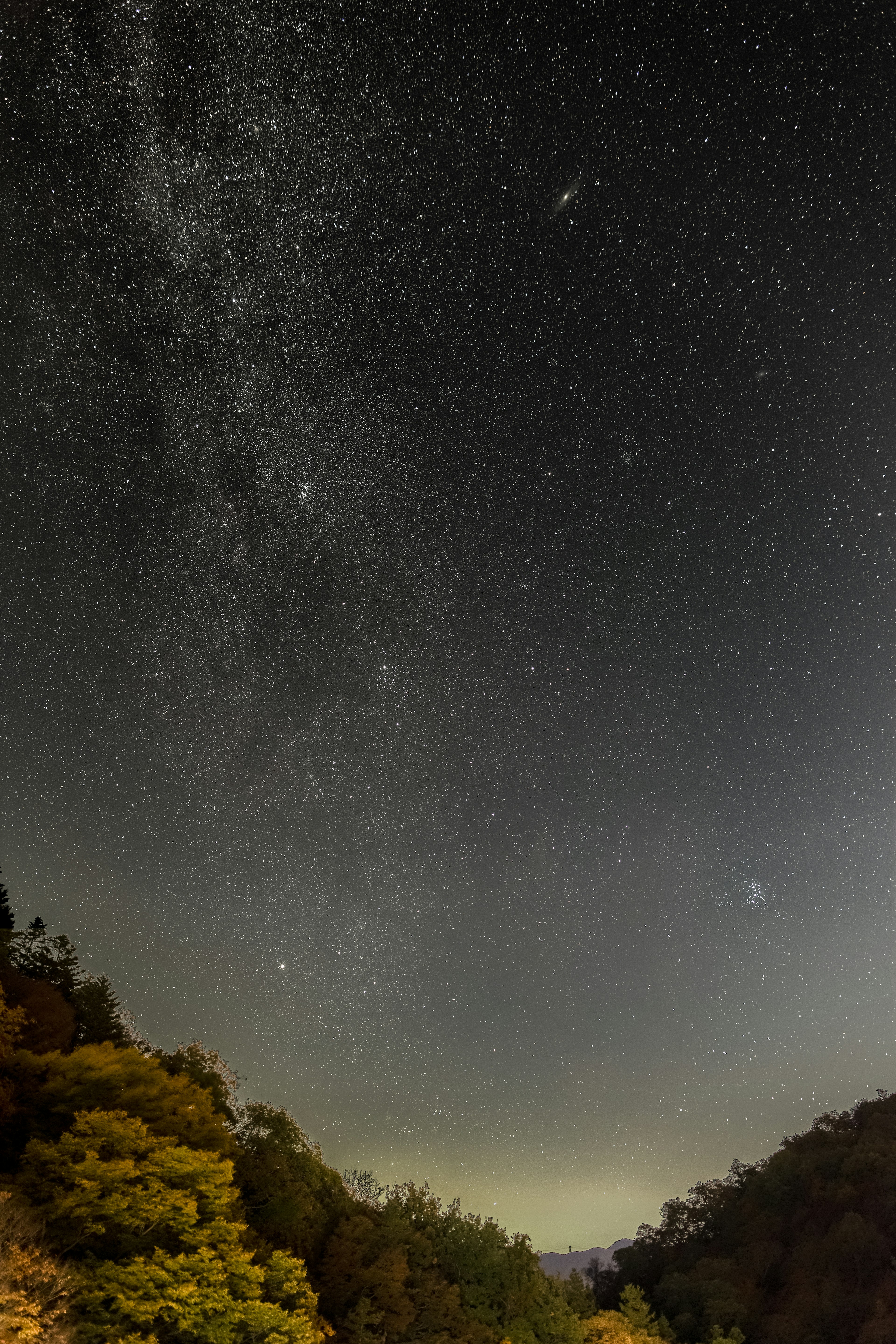 星空の下に広がる銀河の美しい風景と暗い山のシルエット