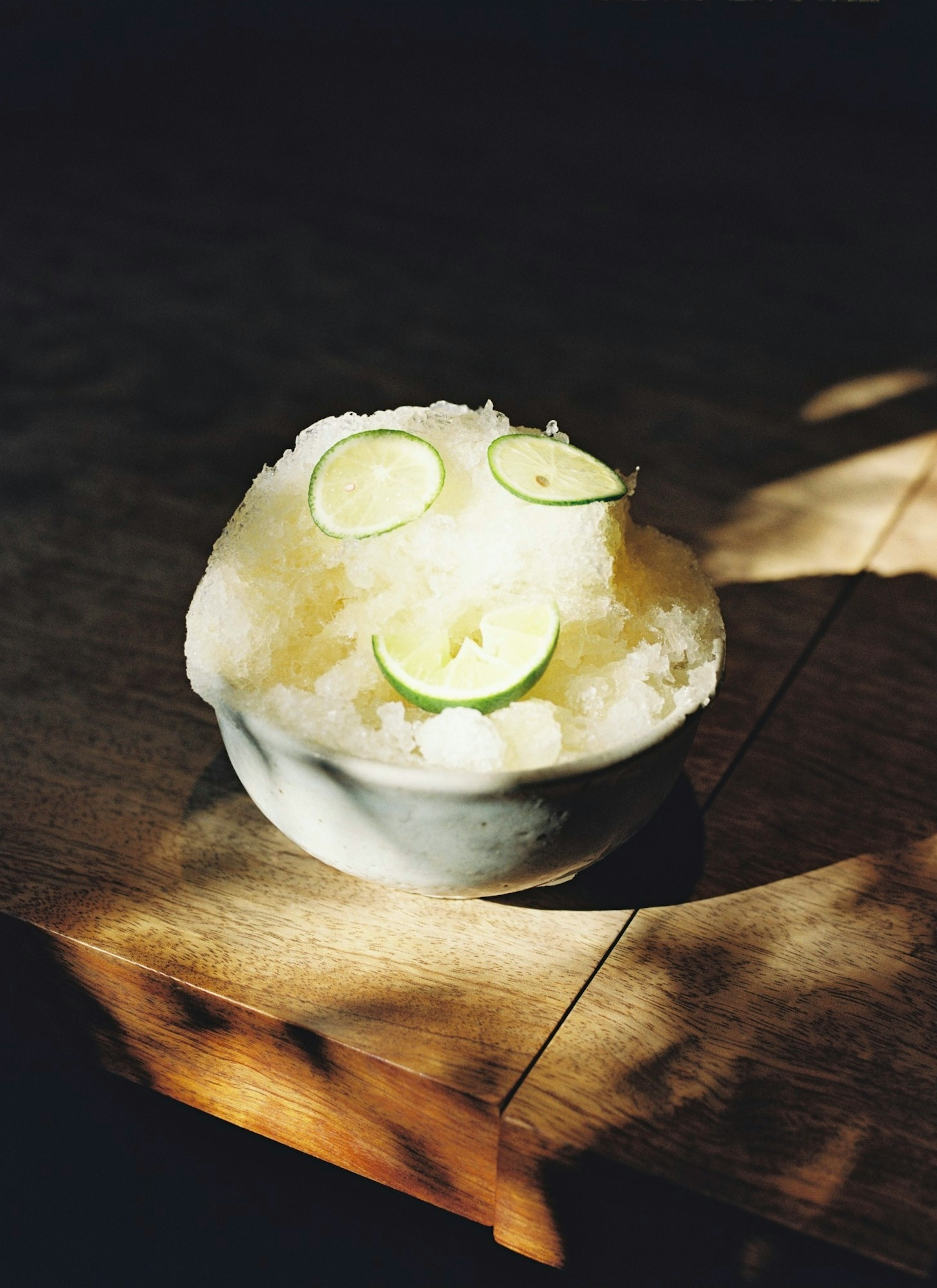 A bowl of shaved ice topped with lime slices creating a cheerful face