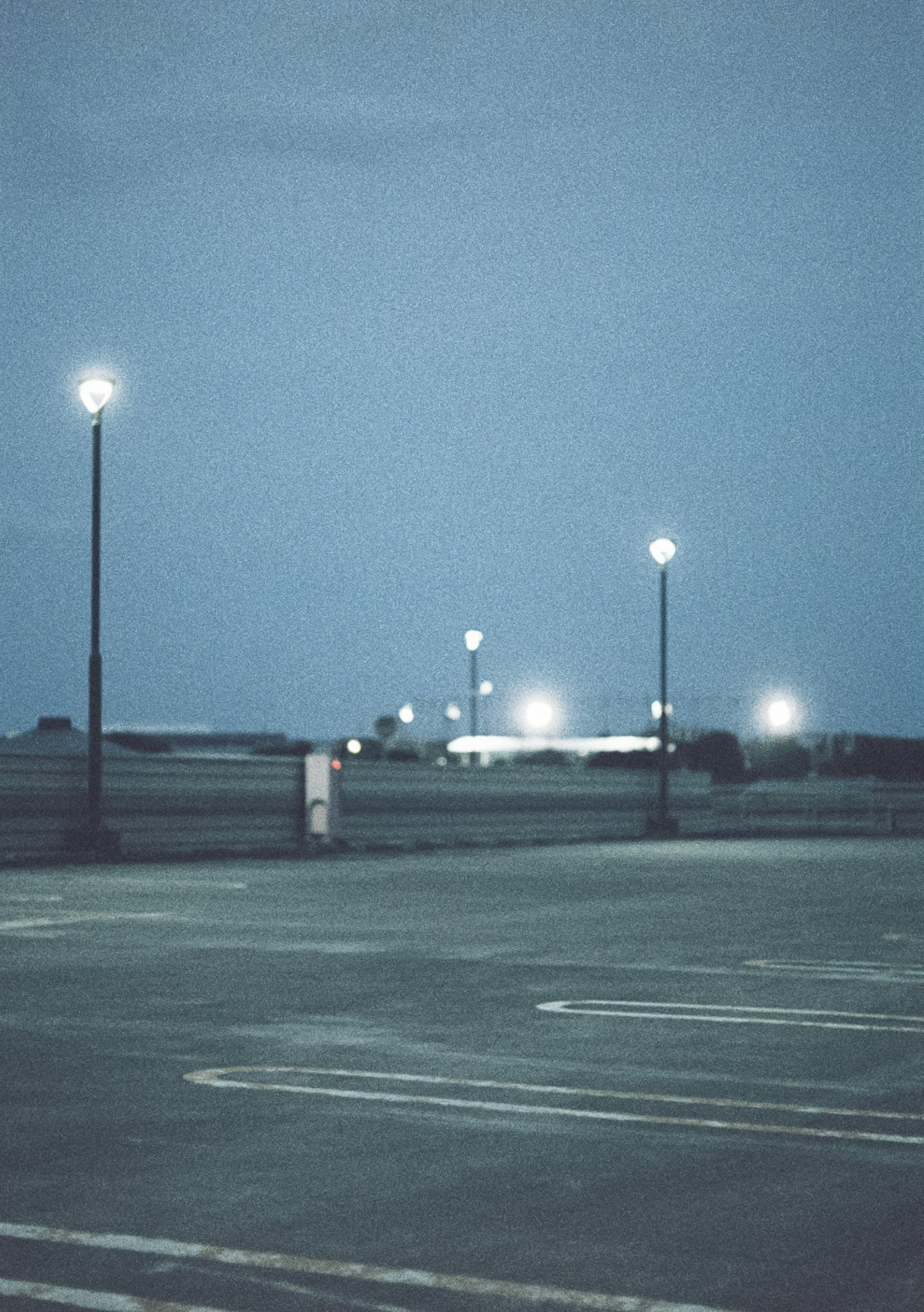 Nighttime parking lot with streetlights and blue sky